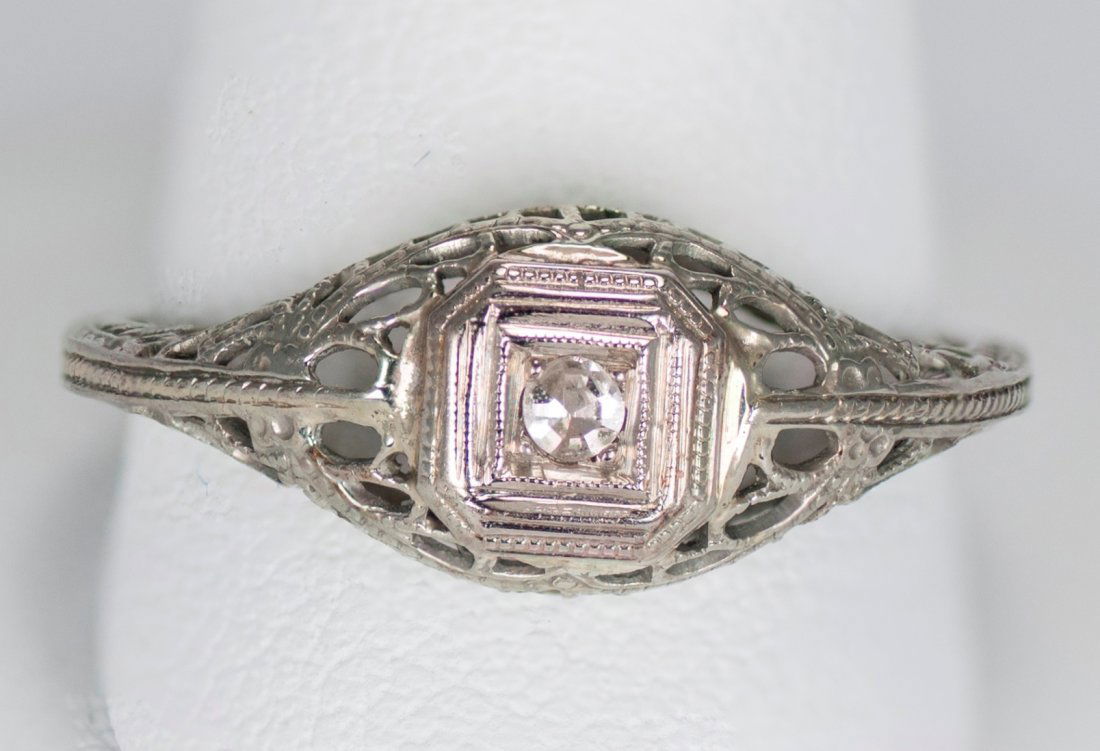 Vintage 18K White Gold Ring with Diamond Solitaire: Antique 18K white gold ring with diamond solitaire surrounded by filigree. Stamped 18K. Ring size is 7. Total ring weight is 0.060 troy ounces, or 1.86 grams. The diamond solitaire weighs 0.07 carats.