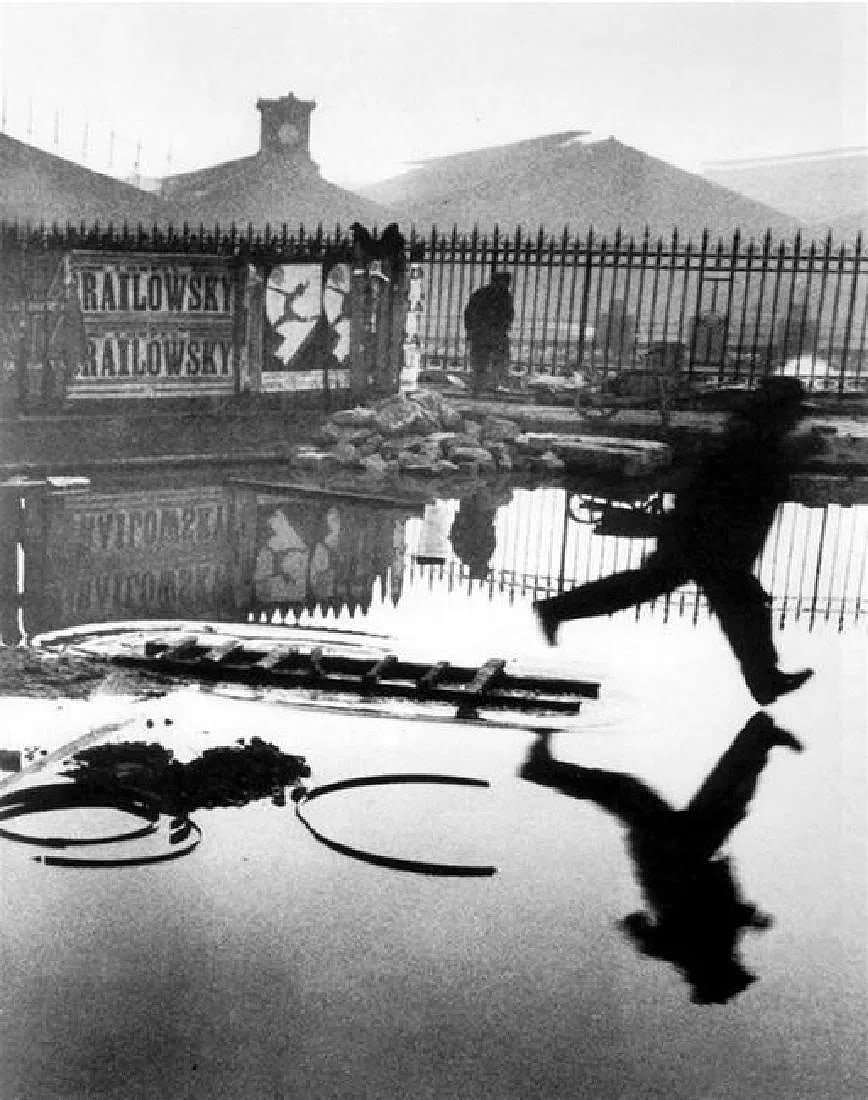 Henri Cartier-Bresson - Behind The Gare St. Lazare: Vintage Sheet-fed Gravure printed in 1955. Perhaps his most famous "decisive moment." Image size: approx. 10" x 13.5"., Mounted to archival board