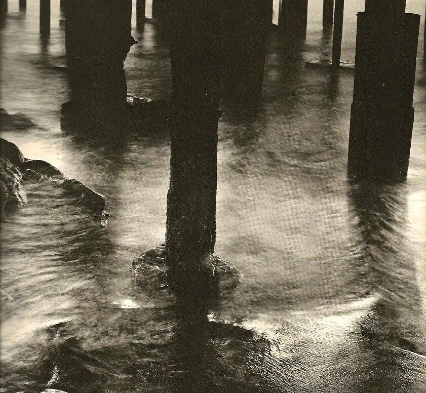 Wynn Bullock - Pilings: Vintage Sheet-fed Gravure. Modernist coastal study. Image size: approx. 8" x 10"., Mounted to archival board