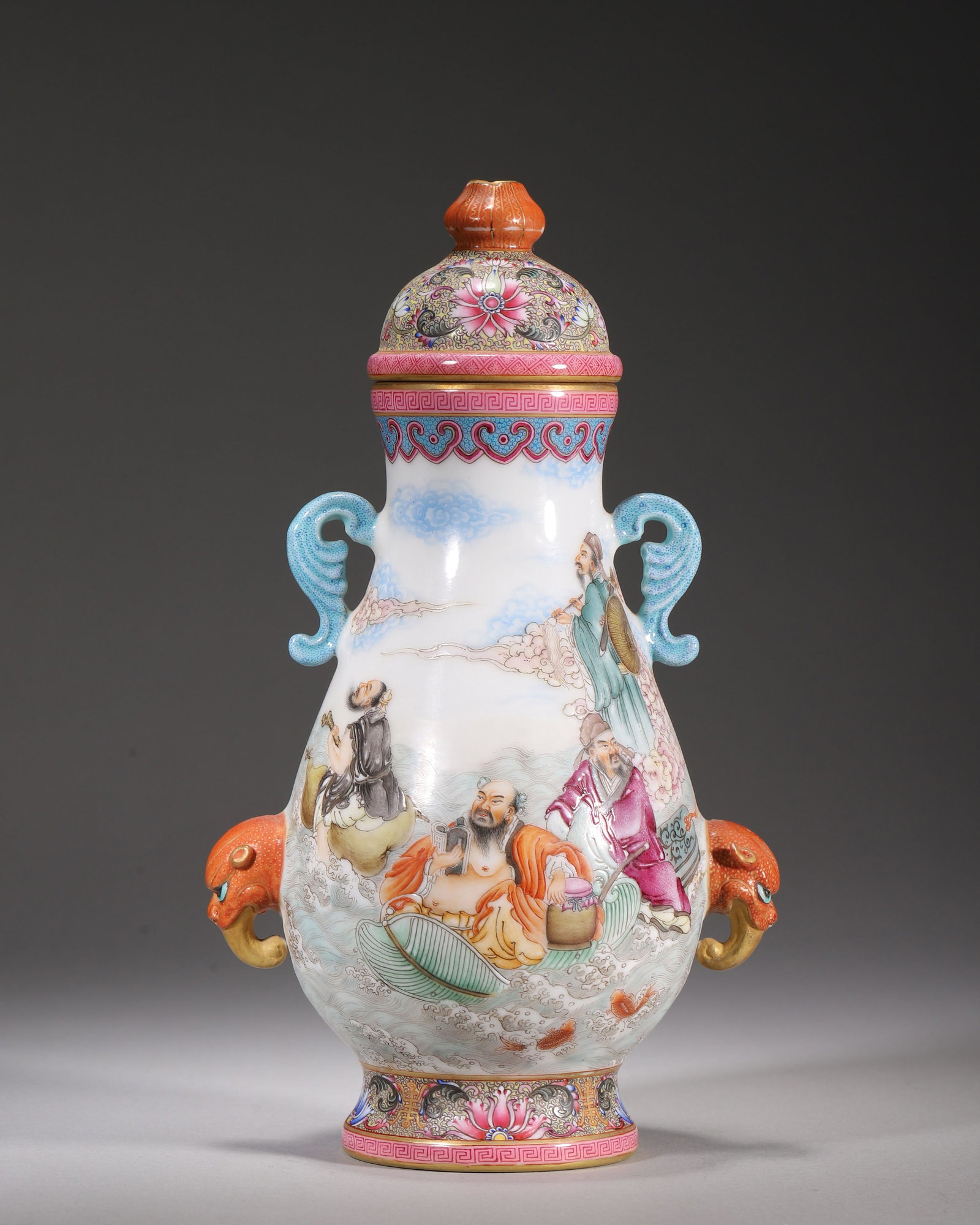 A FAMILLE ROSE GILT COVERED VASE WITH EIGHT IMMORTALS CROSSING THE SEA, QIANLONG PERIOD, QING: H 23.00cm (9.06 in); L 13.00cm (5.12 in); W 10.00cm (3.94 in),Qianlong marked covered porcelain vase with cloud-shaped handles and gilt beast head appliqu??s. Main body finely painted famille rose sce