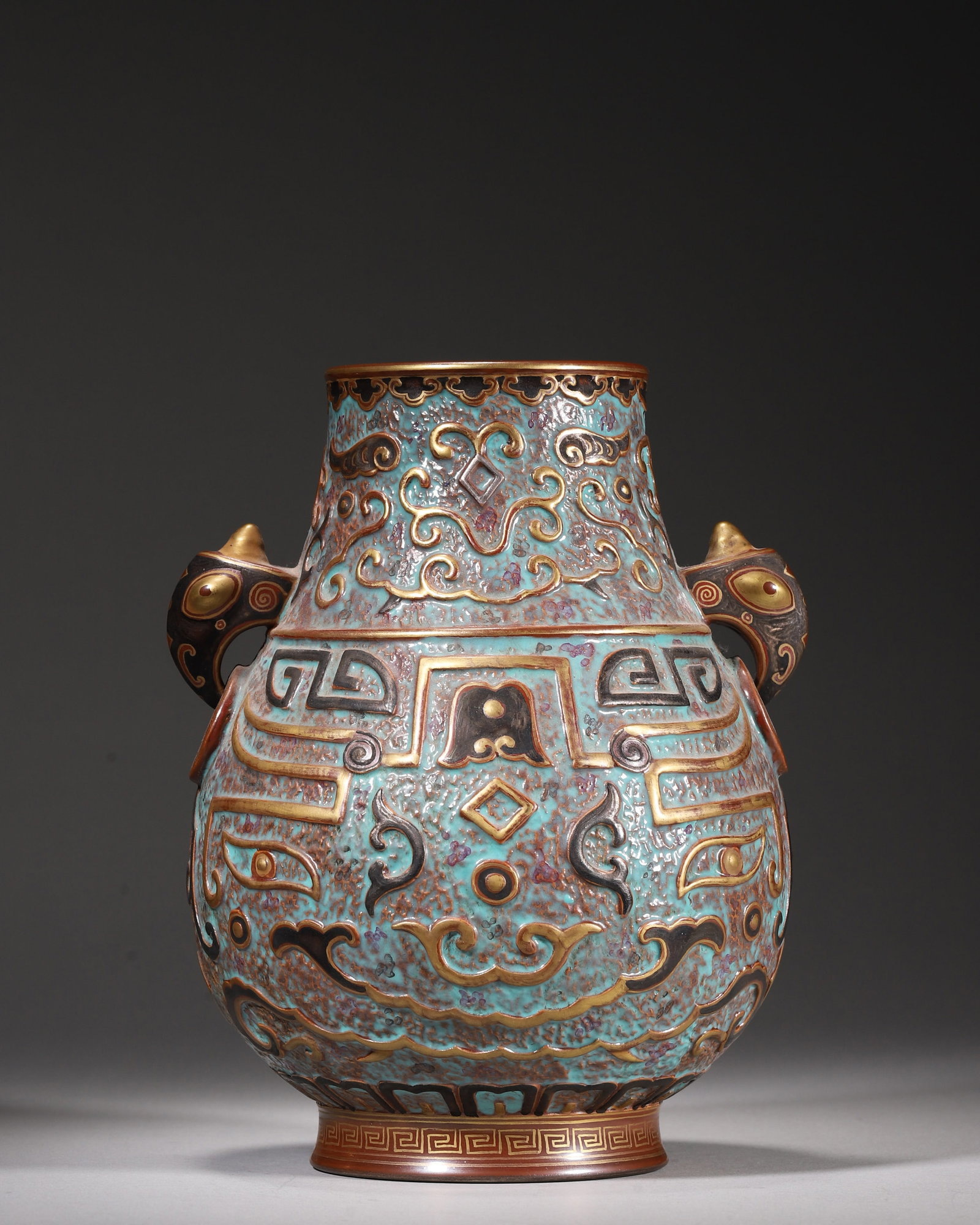 A BRONZE-STYLE GLAZE RELIEF PORCELAIN ZUN WITH GILT & SILVER TAOTIE MASK MOTIF, QIAN LONG NIAN ZHI: H 19.00cm (7.48 in); D 15.00cm (5.91 in),Imperial Qing porcelain ritual zun of Qianlong reign, twin beast-head ring handles. Whole body covered with speckled turquoise bronze-imitation glaze with simu