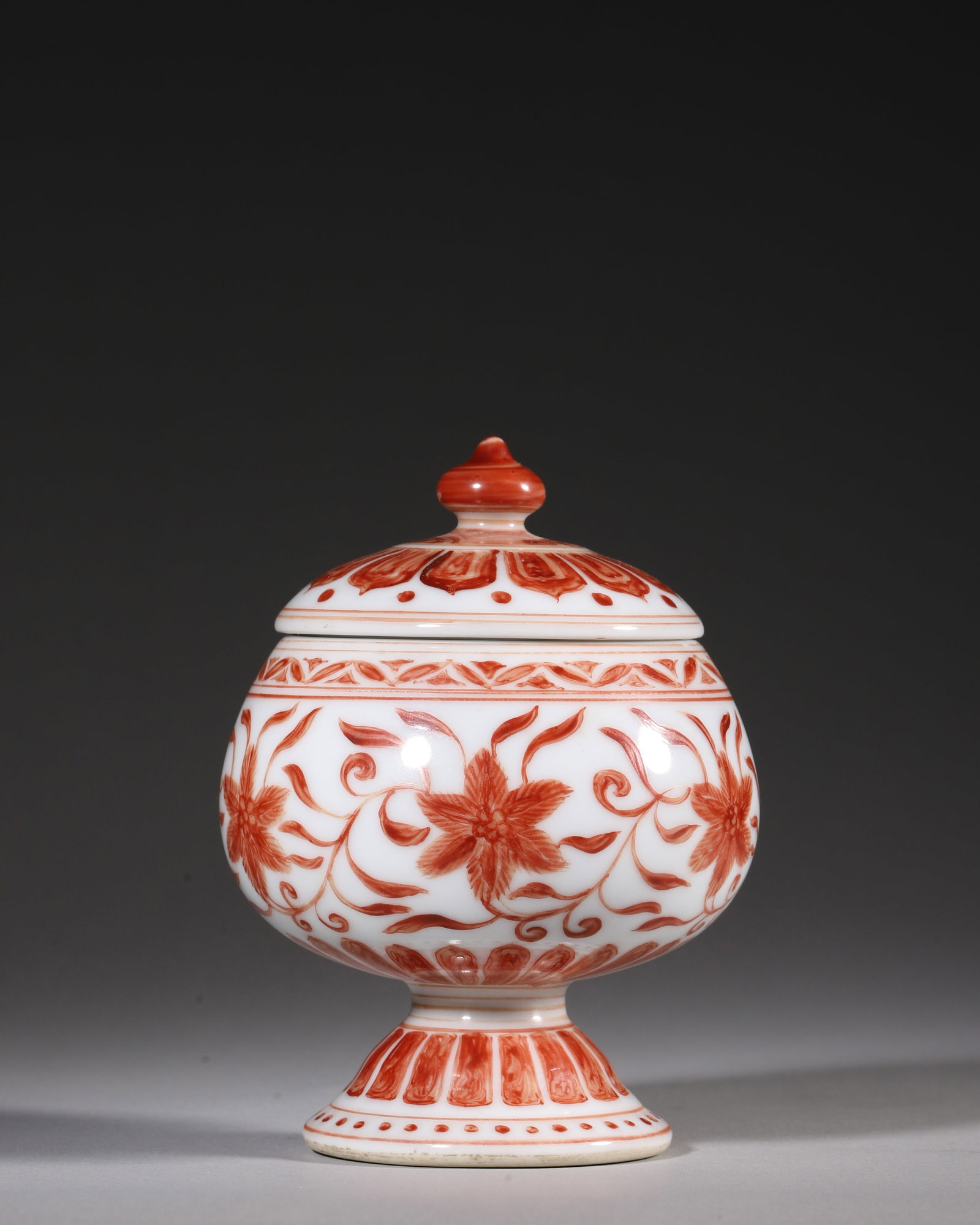 A IRON-RED STEMMED COVERED JAR WITH INTERLOCKING FLORAL SCROLLS, XUANDE PERIOD, MING DYNASTY (1 of 9)