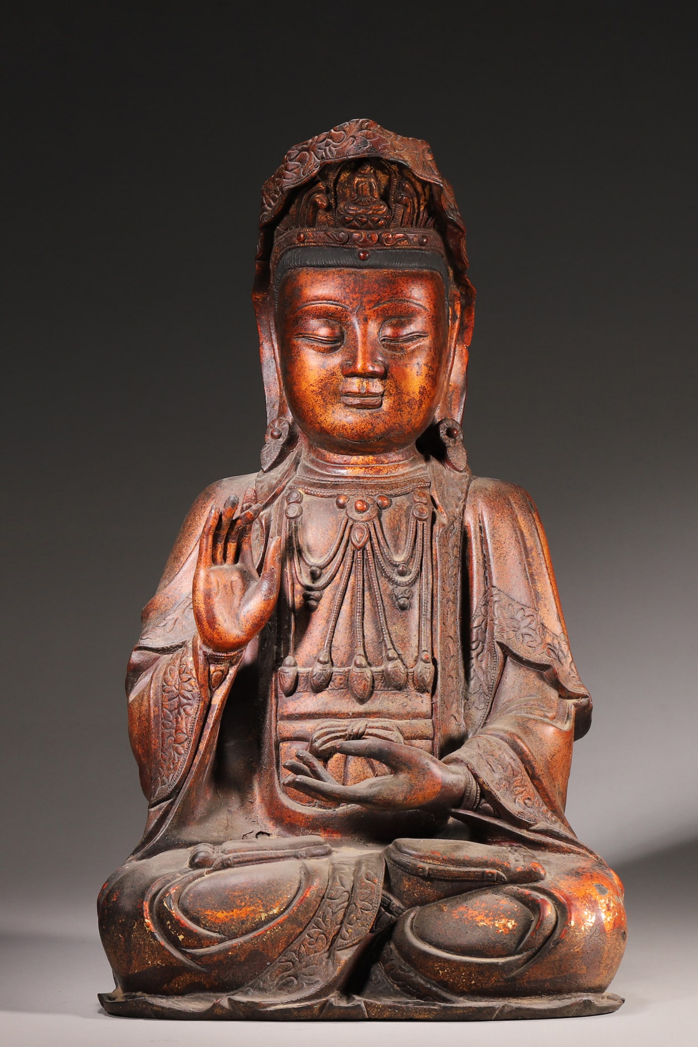 A Lacquered Gilt Bronze Seated Statue of Guanyin, Ming Dynasty: Length 22.0cm (8.66in), Width 17.0cm (6.69in), Height 40.0cm (15.75in), Weight 8505.0g (18.75lb)A lacquered gilt bronze seated statue of Guanyin from the Ming Dynasty. The serene-faced Bodhisattva wea