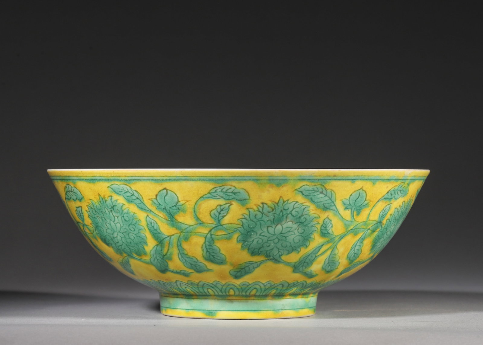 A YELLOW GROUND GREEN ENAMEL BOWL, XUANDE PERIOD MING DYNASTY: W 20cm (7.87 in); H 8cm (3.15 in),A Ming Xuande bowl with yellow ground and green interlocking peony scrolls, plain white interior, lotus band around foot. Six-character Xuande reign mark in double ci