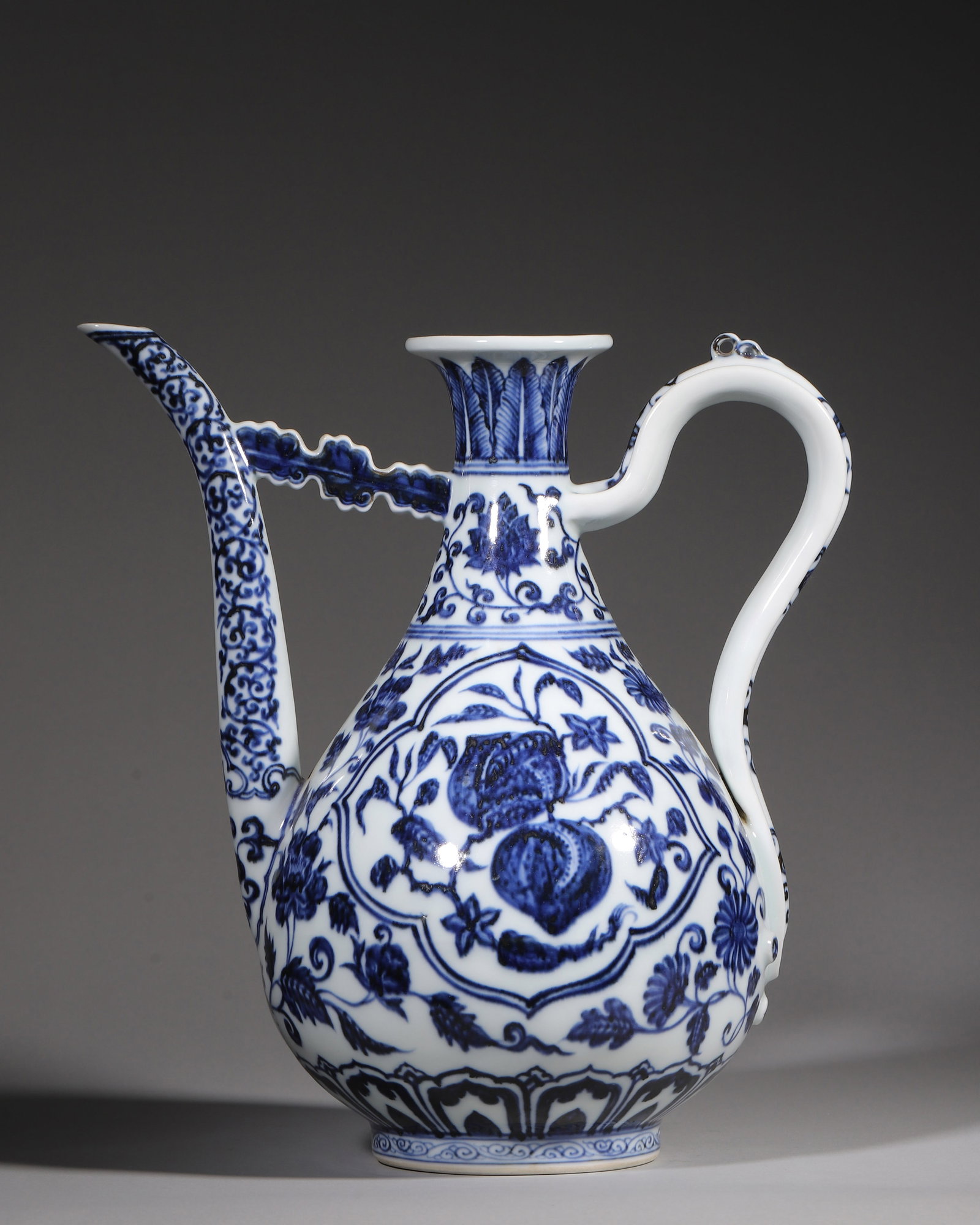 A BLUE AND WHITE EWER WITH FRUITS IN CARTOUCHE DESIGN, YONGLE PERIOD, MING DYNASTY: W 28cm (11.02 in); H 29cm (11.42 in),A Ming Yongle official blue and white pear-shaped ewer with sand base, painted with peach, lychee fruits inside cartouches, surrounded by four-season floral scroll
