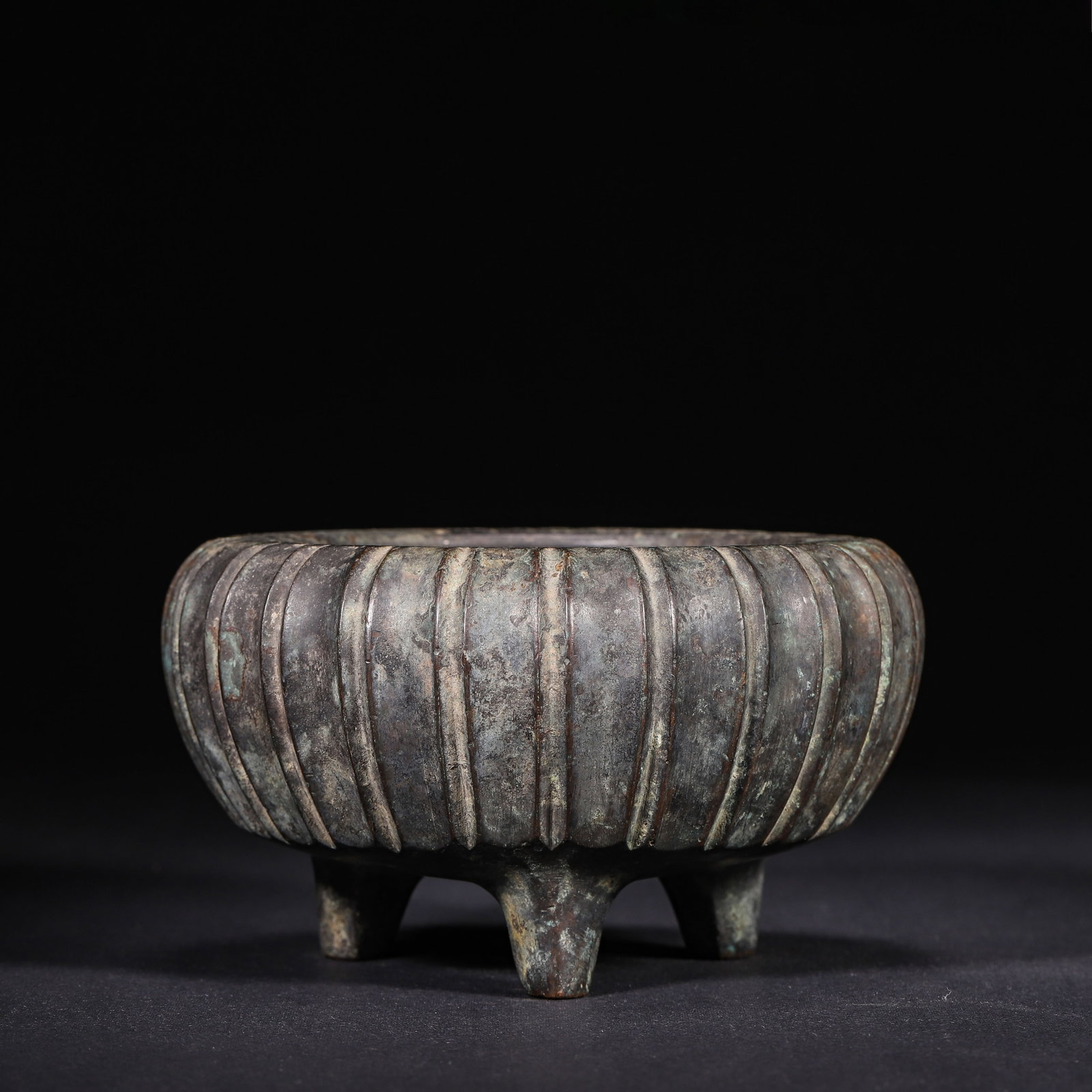 Bronze Melon-Ribbed Tripod Censer, Xuande Period, Ming Dynasty: Wt 1212g (2.67 lb); D 14cm (5.51 in); H 8cm (3.15 in)Finely cast bronze tripod censer of Xuande period. Wide opening, the body adorned with vertical melon ribs. Supported by three feet. Thick body cov