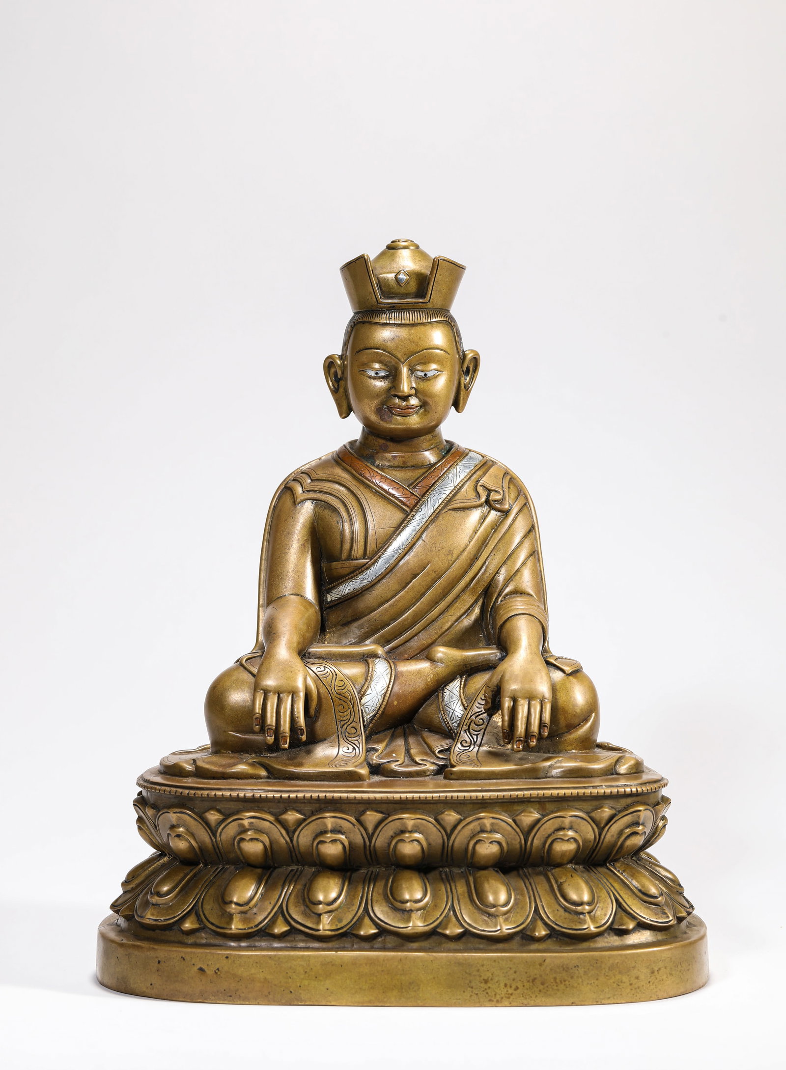 A Gilt-Bronze, Silver and Copper-Inlaid Figure of Buddha: A Gilt-Bronze, Silver and Copper-Inlaid Figure of Buddha Dimensions: Weight: 3.9kg. Length: 22.0 cm (8.66 in) x Width: 16.2 cm (6.38 in) x Height: 27.0 cm (10.63 in). All measurements are approximate.