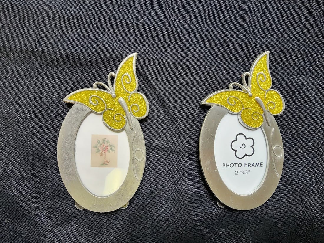 Pair of Yellow Butterfly Oval Picture Frames: Lovely set of two oval metal picture frames adorned with bright yellow glitter butterflies. Each frame holds a 2” x 3” photo and features a smooth silver-tone finish. Perfect for spring d�