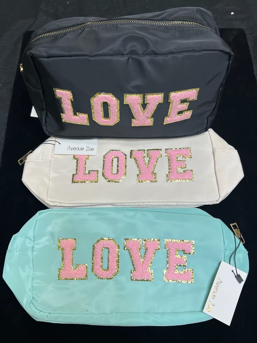 AVENUE ZOE "LOVE" COSMETIC BAGS - SET OF 3: Spread some sparkle with these Avenue Zoe zippered cosmetic bags, each featuring the word LOVE in plush pink lettering outlined in gold glitter. The set includes three stylish colors — classic black