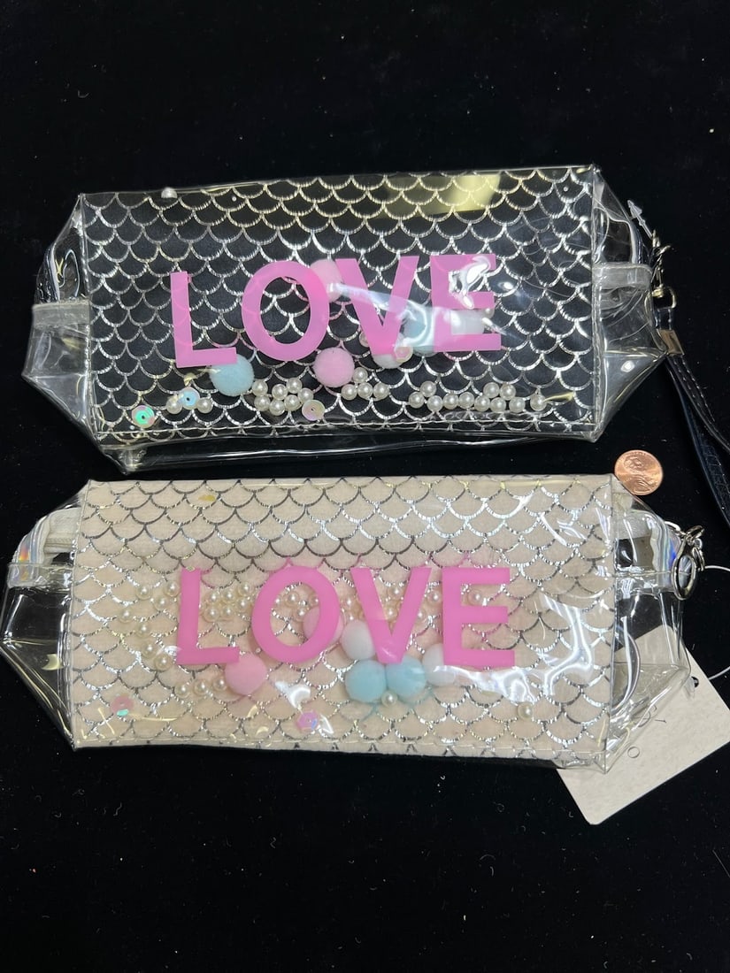 SET OF 2 "LOVE" COSMETIC BAGS - BLACK & WHITE MERMAID SCALES WITH FLOATING PEARLS: This adorable set of two cosmetic bags includes one black and one white pouch, both featuring a shimmery mermaid-scale pattern beneath a clear outer layer. Each bag has floating pastel pom-poms, pearl