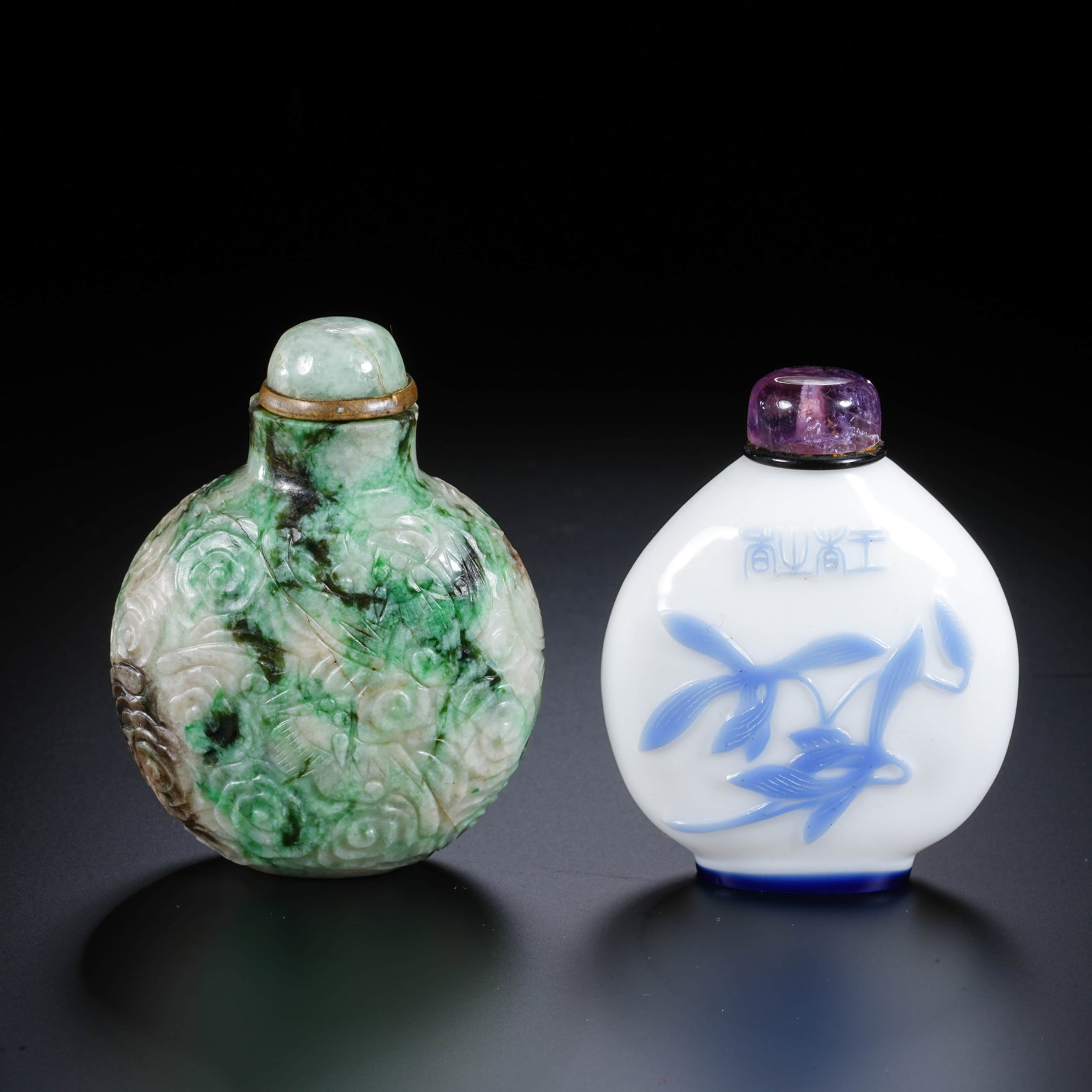A CHINESE JADEITE AND GLASS SNUFF BOTTLE: This pair consists of two snuff bottles of varying materials and craftsmanship. The snuff bottle on the left features a well-rounded body carved from jadeite, entirely decorated in low relief with an 