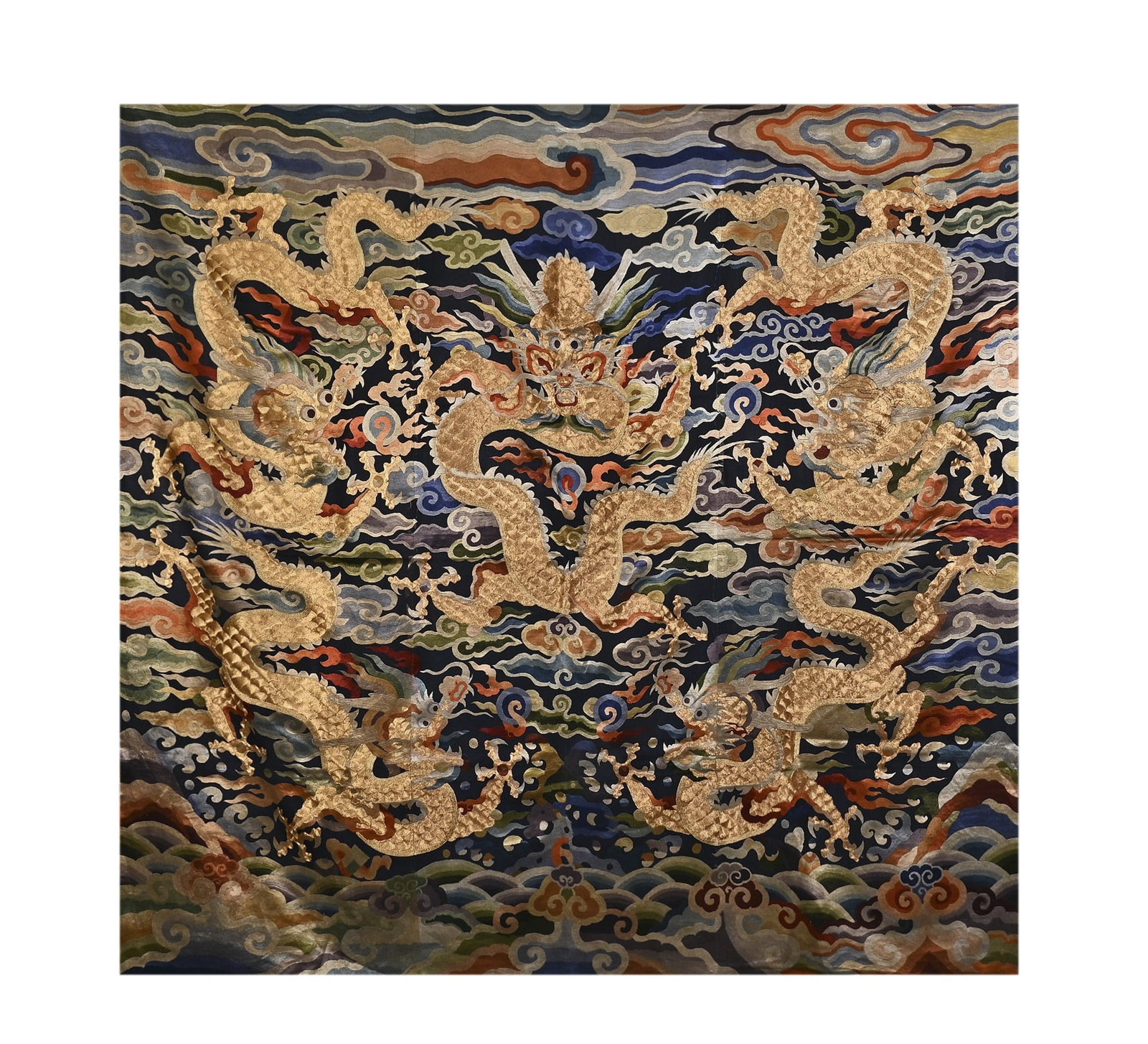 A CHINESE KESI 'FIVE DRAGONS PLAYING WITH A PEARL' FABRIC: This square embroidered textile (possibly a hanging panel or rug) is crafted on a deep navy blue silk ground, decorated with a grand and powerful composition of multiple golden dragons surging through