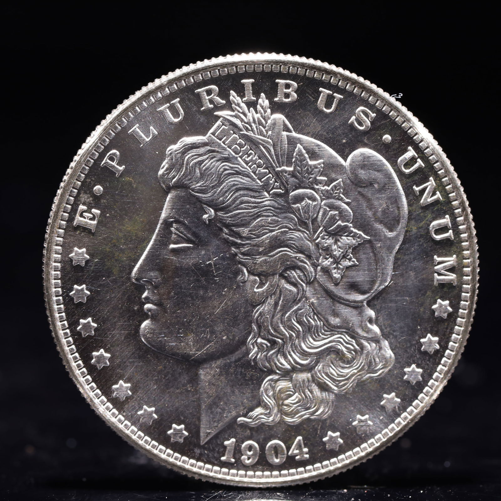 USA Morgan Dollar 1904 Coin: Obv: profile bust with date below and E PLURIBUS UNUM legend and stars around. Rev: eagle with In God we trust above within wreath with UNITED STATES OF AMERICA ONE DOLLAR legend. IN GOD WE TRUST / LI