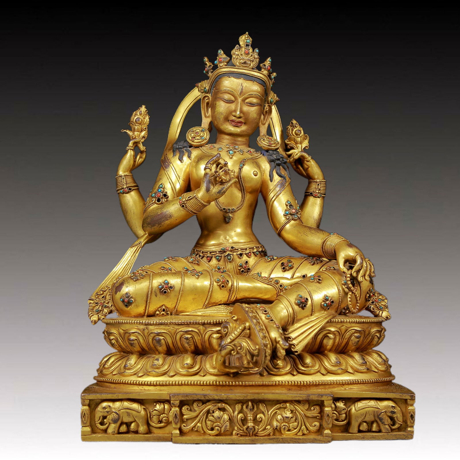 A solemn gilt bronze statue of green Tara inlaid with sapphires: solemn gilt bronze statue of green Tara Ming Dynasty, China. Tara has an elegant posture with a peaceful and compassionate expression. Her face is soft and solemn, and her eyes are warm. She seems to