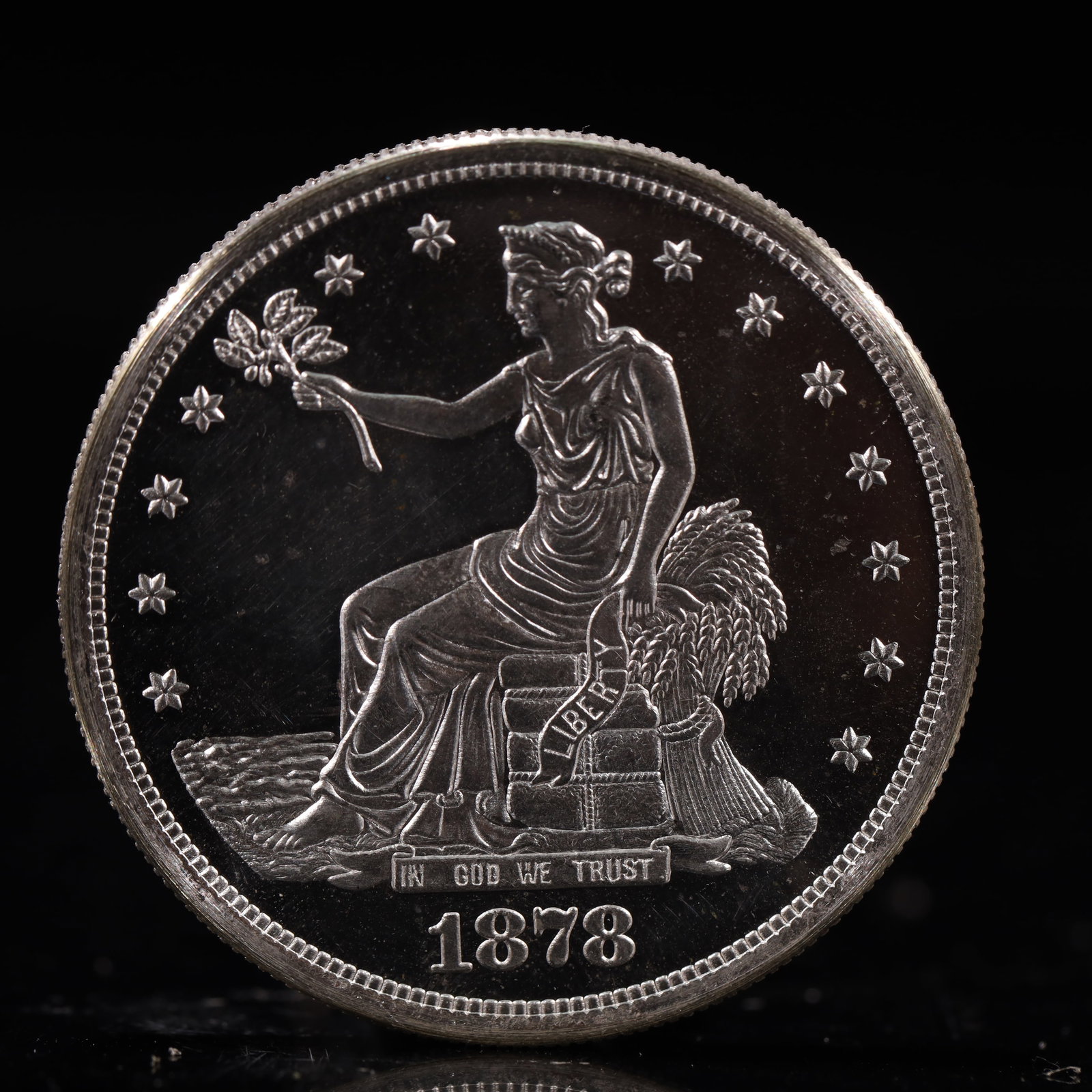 USA Trade Dollar 1878 Coin: American coin. Obverse: Liberty seated on a pedestal facing the sea to the left holding olive branches surrounded by 13 stars. IN GOD WE TRUST / LIBERTY / 1878. Reverse: An eagle holding branches with