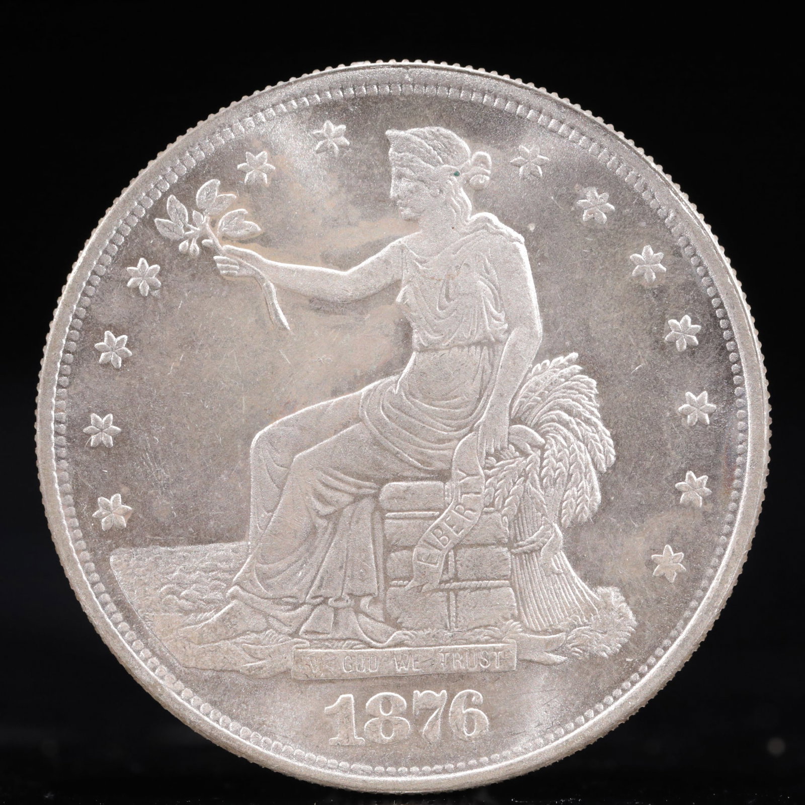 USA Trade Dollar 1876 Coin: American coin. Obverse: Liberty seated on a pedestal facing the sea to the left holding olive branches surrounded by 13 stars. IN GOD WE TRUST / LIBERTY / 1876. Reverse: An eagle holding branches with