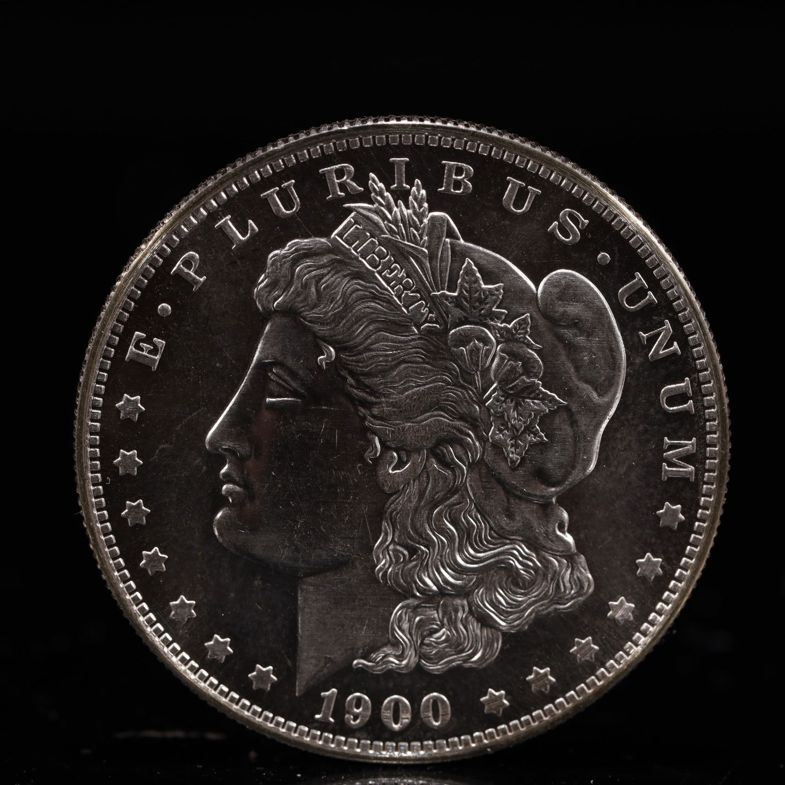 USA Morgan Dollar 1900 Coin: Obv: profile bust with date below and E PLURIBUS UNUM legend and stars around. Rev: eagle with In God we trust above within wreath with UNITED STATES OF AMERICA ONE DOLLAR legend. IN GOD WE TRUST / LI