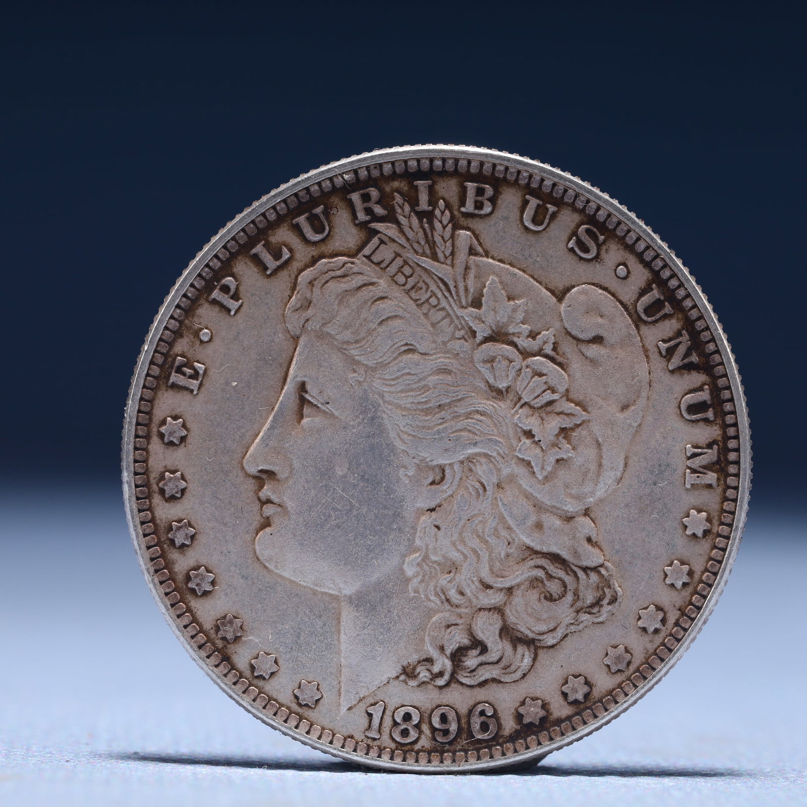 USA Morgan Dollar 1896 Coin: Obv: profile bust with date below and E PLURIBUS UNUM legend and stars around. Rev: eagle with In God we trust above within wreath with UNITED STATES OF AMERICA ONE DOLLAR legend. IN GOD WE TRUST /