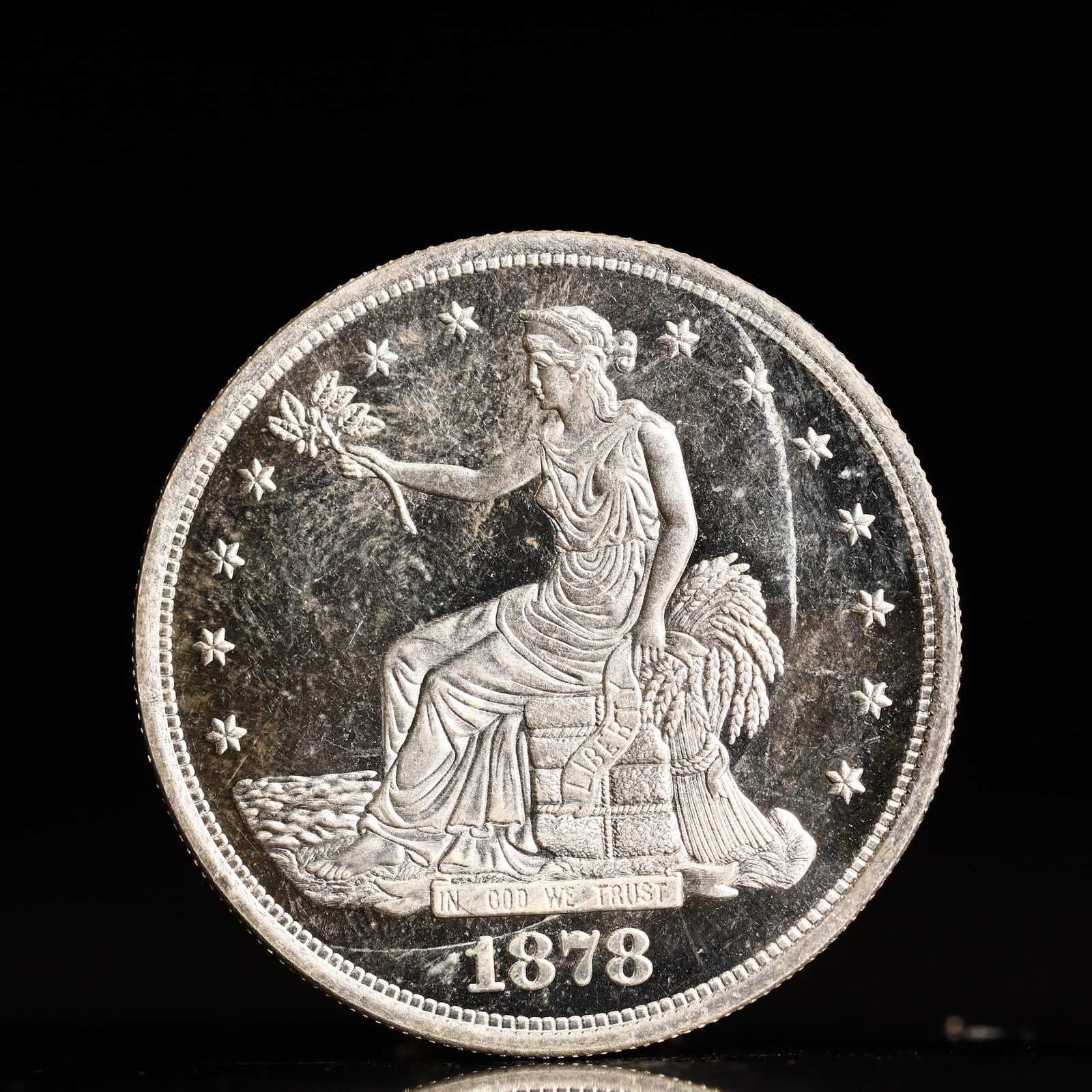 USA Trade Dollar 1878 Coin: American coin. Obverse: Liberty seated on a pedestal facing the sea to the left holding olive branches surrounded by 13 stars. IN GOD WE TRUST / LIBERTY / 1878. Reverse: An eagle holding branches with