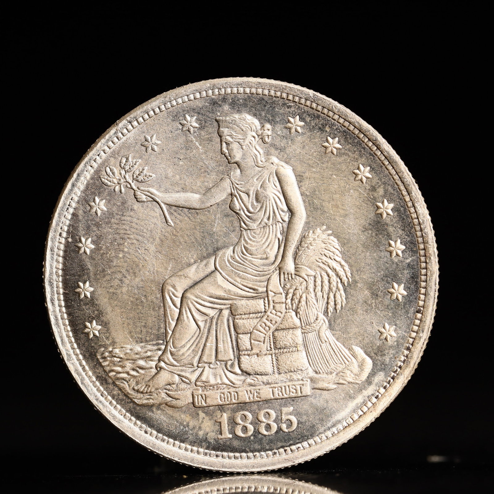USA Trade Dollar 1885 Coin: American coin. Obverse: Liberty seated on a pedestal facing the sea to the left holding olive branches surrounded by 13 stars. IN GOD WE TRUST / LIBERTY / 1885. Reverse: An eagle holding branches with