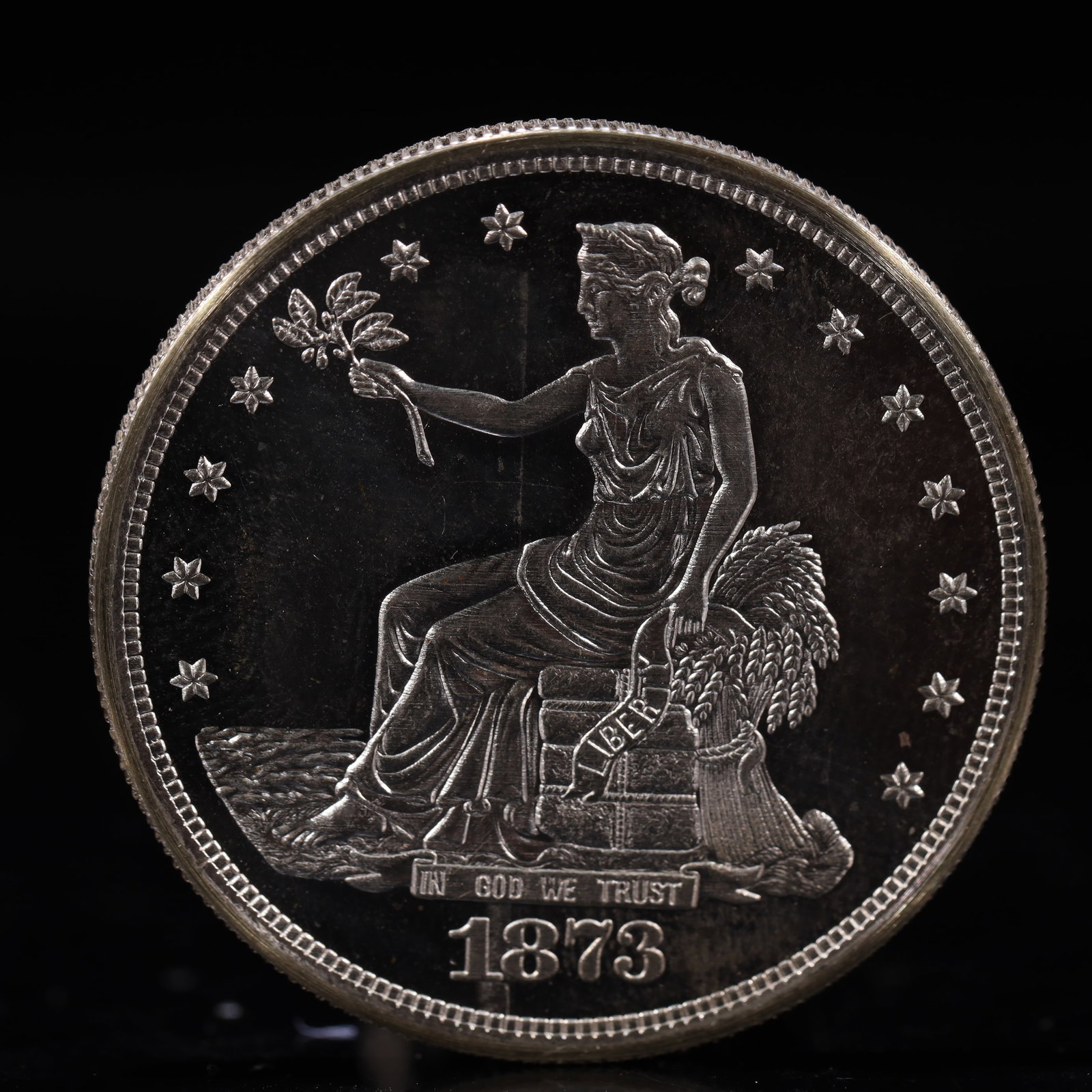 USA Trade Dollar 1873 Coin: American coin. Obverse: Liberty seated on a pedestal facing the sea to the left holding olive branches surrounded by 13 stars. IN GOD WE TRUST / LIBERTY / 1873. Reverse: An eagle holding branches
