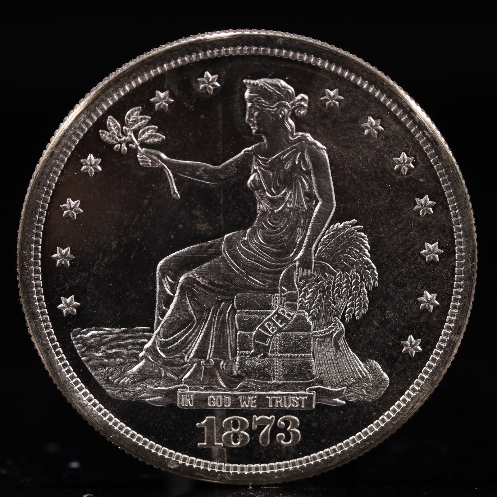 USA Trade Dollar 1873 Coin: American coin. Obverse: Liberty seated on a pedestal facing the sea to the left holding olive branches surrounded by 13 stars. IN GOD WE TRUST / LIBERTY / 1873. Reverse: An eagle holding branches