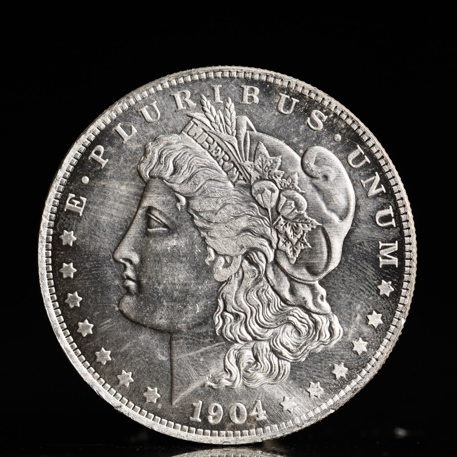 USA Morgan Dollar 1904 Coin: Obv: profile bust with date below and E PLURIBUS UNUM legend and stars around. Rev: eagle with In God we trust above within wreath with UNITED STATES OF AMERICA ONE DOLLAR legend. IN GOD WE TRUST / LI