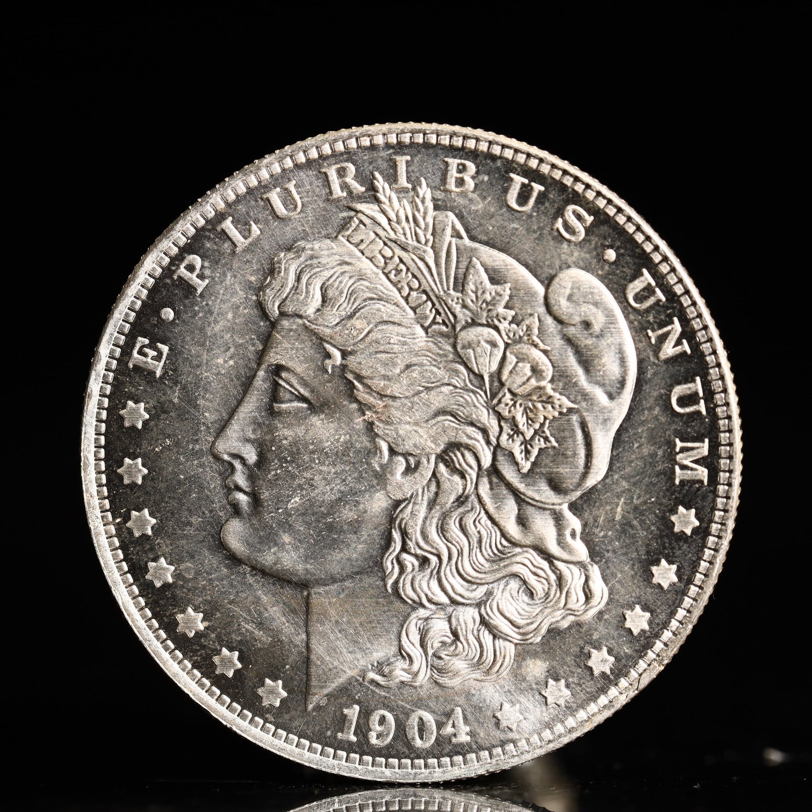 USA Morgan Dollar 1904 Coin: Obv: profile bust with date below and E PLURIBUS UNUM legend and stars around. Rev: eagle with In God we trust above within wreath with UNITED STATES OF AMERICA ONE DOLLAR legend. IN GOD WE TRUST / LI