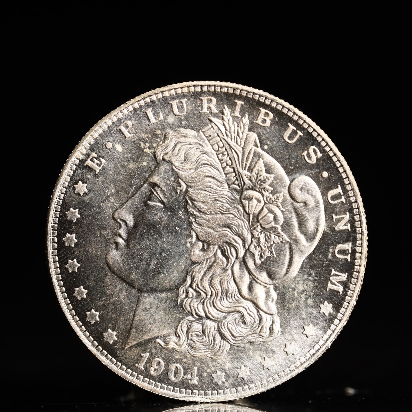 USA Morgan Dollar 1904 Coin: Obv: profile bust with date below and E PLURIBUS UNUM legend and stars around. Rev: eagle with In God we trust above within wreath with UNITED STATES OF AMERICA ONE DOLLAR legend. IN GOD WE TRUST / LI