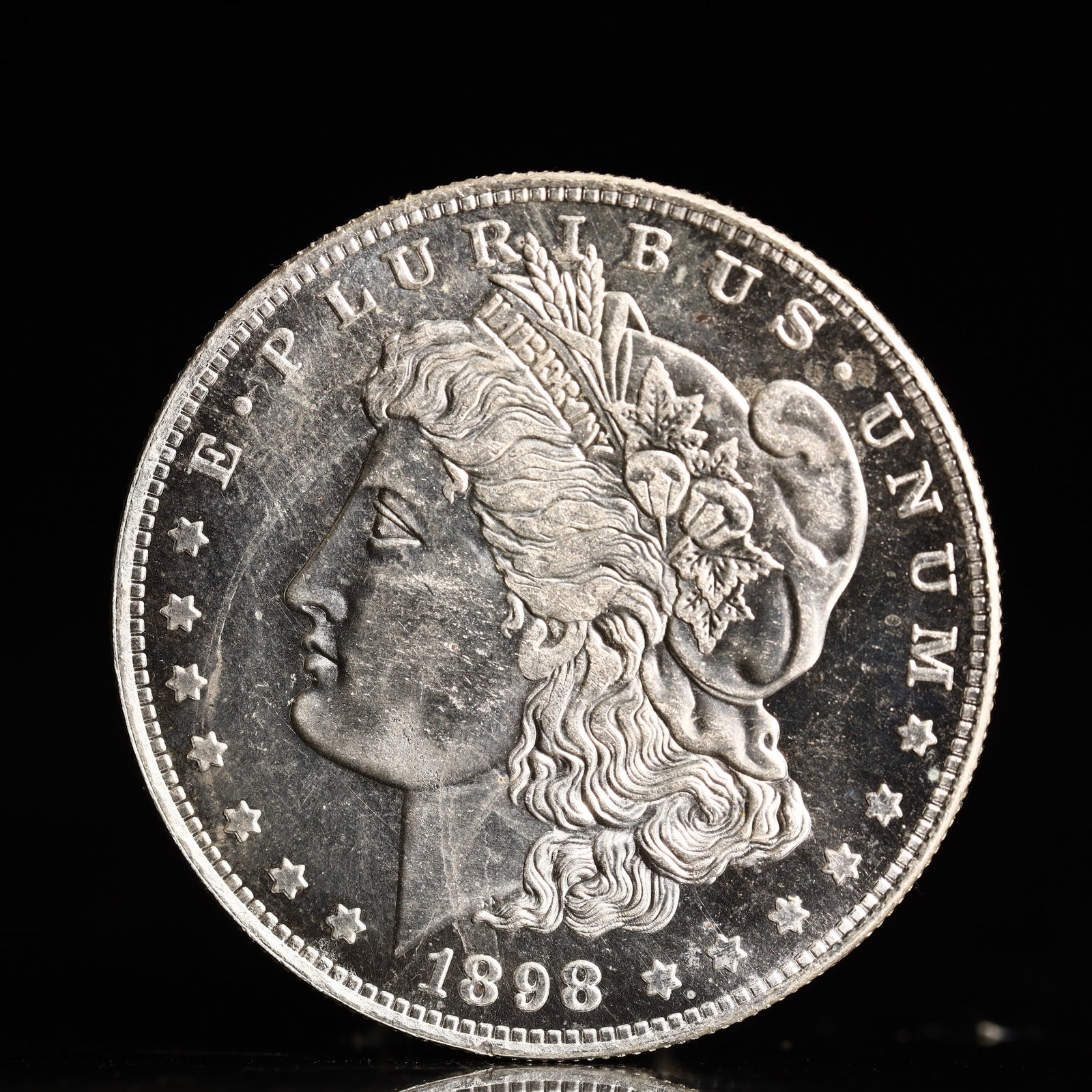 USA Morgan Dollar 1898 Coin: Obv: profile bust with date below and E PLURIBUS UNUM legend and stars around. Rev: eagle with In God we trust above within wreath with UNITED STATES OF AMERICA ONE DOLLAR legend. IN GOD WE TRUST / LI