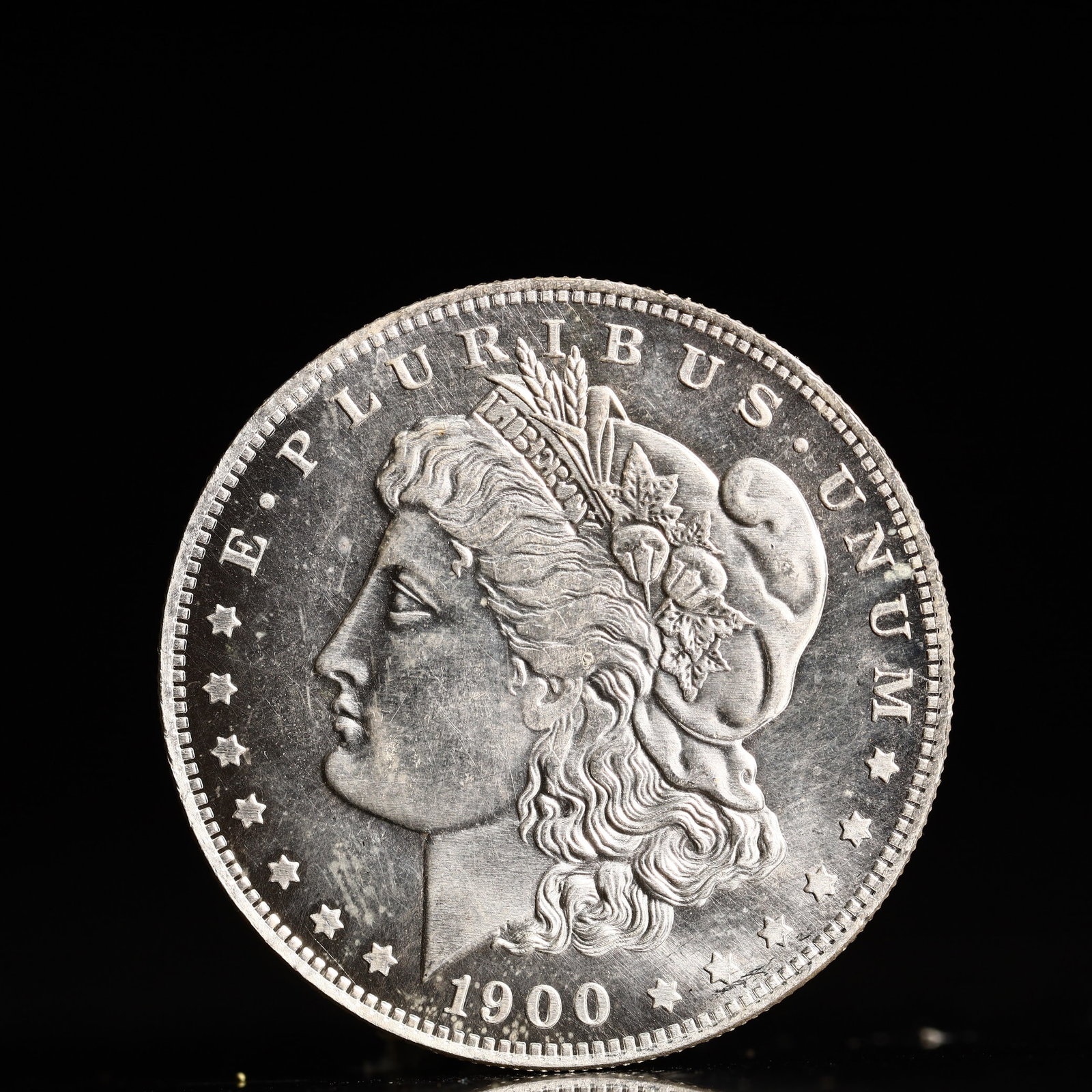 USA Morgan Dollar 1900 Coin: Obv: profile bust with date below and E PLURIBUS UNUM legend and stars around. Rev: eagle with In God we trust above within wreath with UNITED STATES OF AMERICA ONE DOLLAR legend. IN GOD WE TRUST / LI