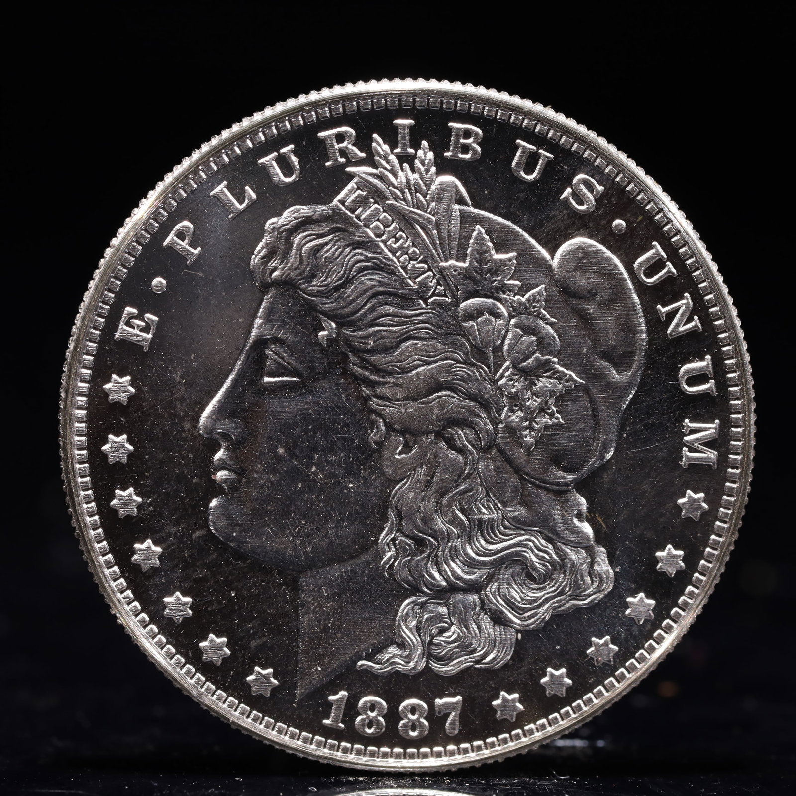 USA Morgan Dollar 1887 Coin: Obv: profile bust with date below and E PLURIBUS UNUM legend and stars around. Rev: eagle with In God we trust above within wreath with UNITED STATES OF AMERICA ONE DOLLAR legend. IN GOD WE TRUST /