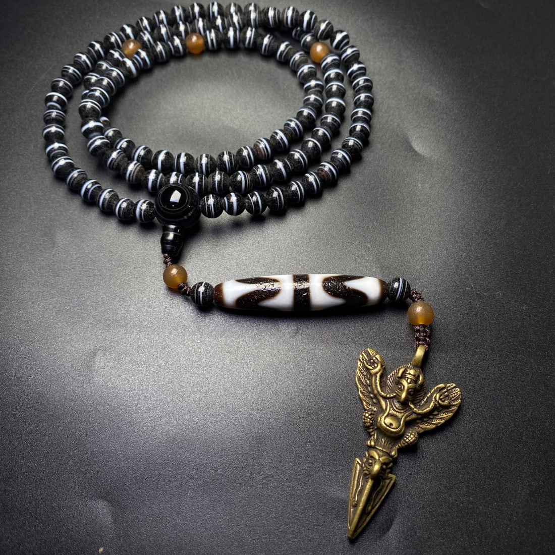 An Exquisite Dzi Bead Necklace,With Bronze Roc Pendant: An Exquisite Dzi Bead Necklace,With Bronze Roc Pendant,Size:8mm,(Dzi Bead)56mmx12mm 天珠项链,带铜大鹏鸟挂件