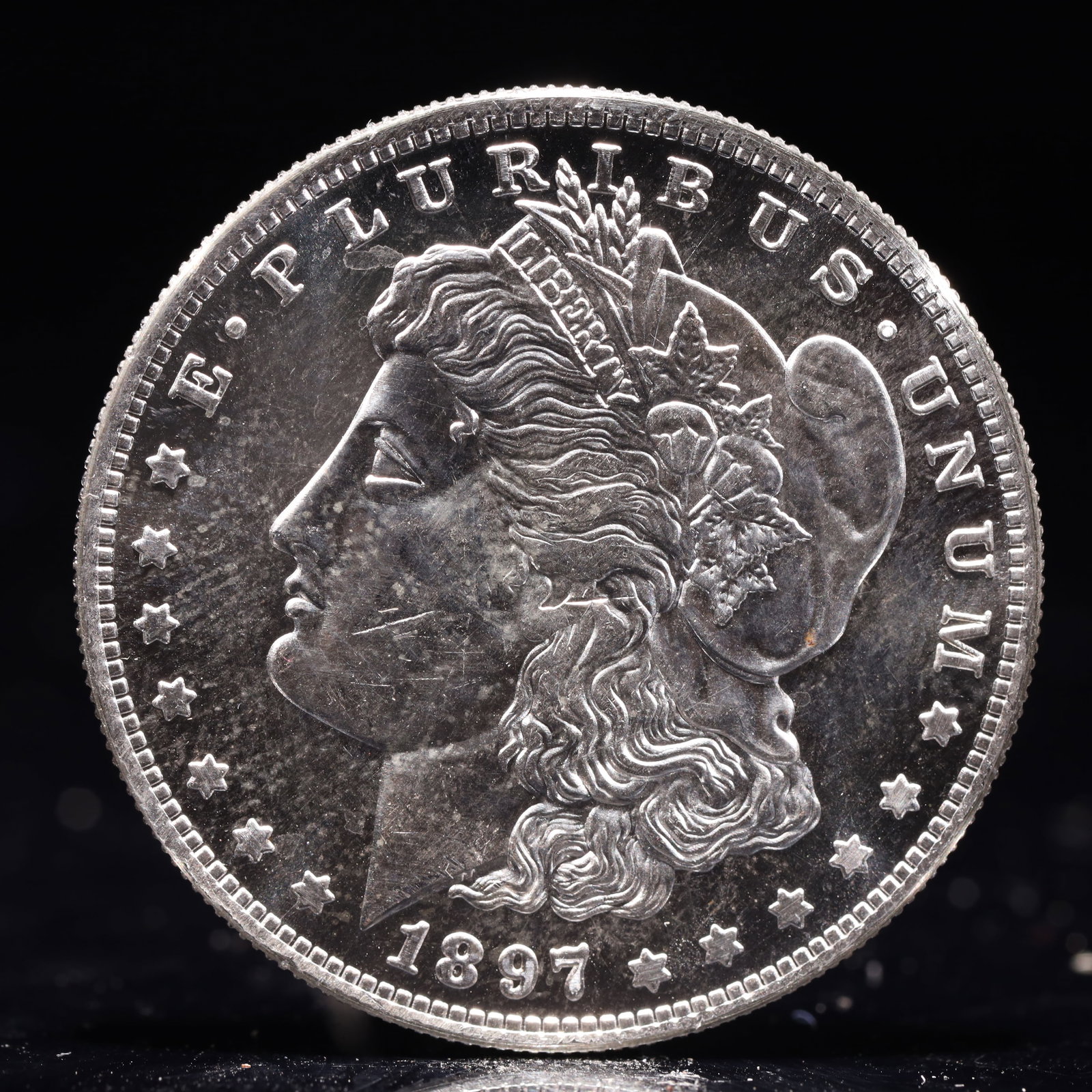 USA Morgan Dollar 1897 Coin: Obv: profile bust with date below and E PLURIBUS UNUM legend and stars around. Rev: eagle with In God we trust above within wreath with UNITED STATES OF AMERICA ONE DOLLAR legend. IN GOD WE TRUST /