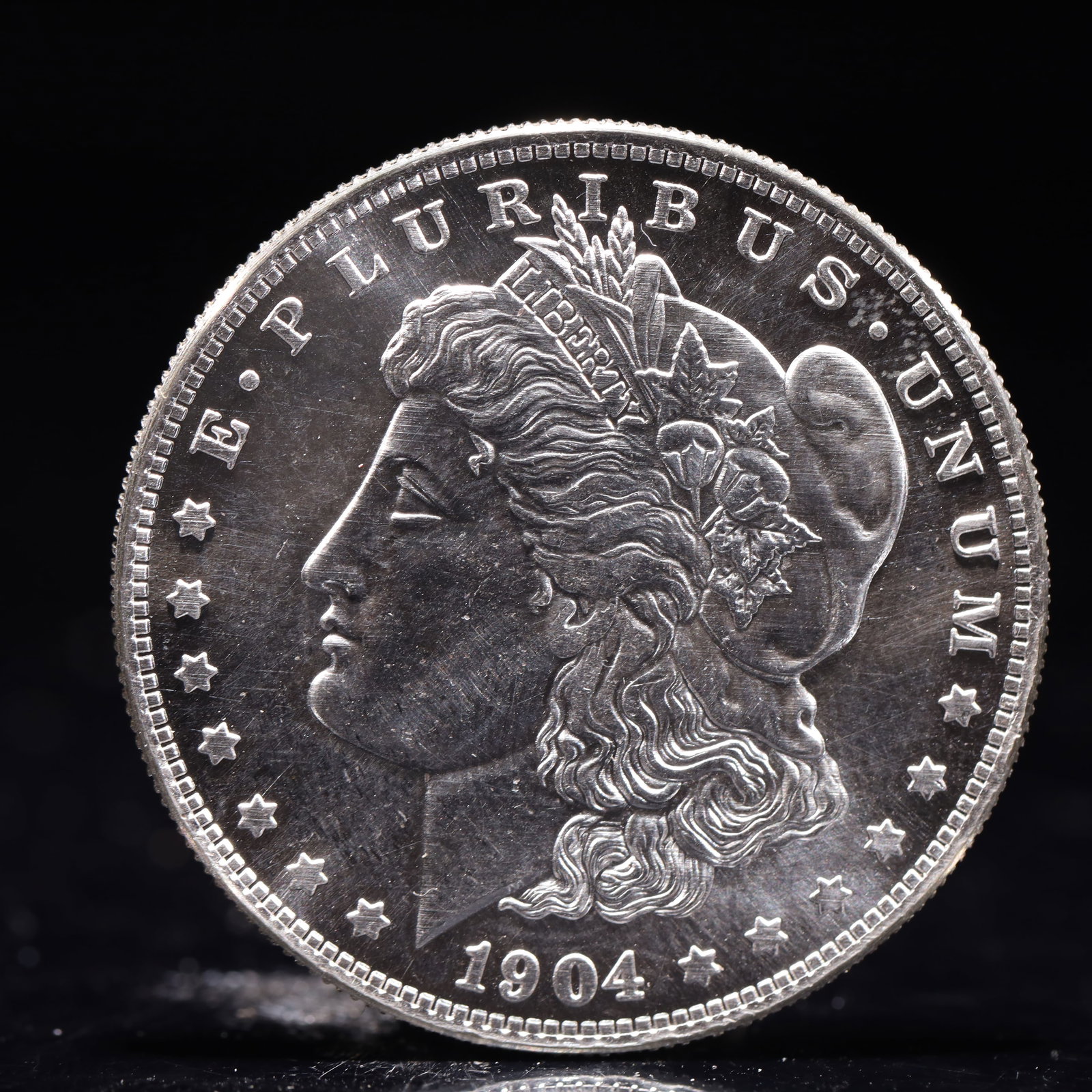 USA Morgan Dollar 1904 Coin: Obv: profile bust with date below and E PLURIBUS UNUM legend and stars around. Rev: eagle with In God we trust above within wreath with UNITED STATES OF AMERICA ONE DOLLAR legend. IN GOD WE TRUST / LI