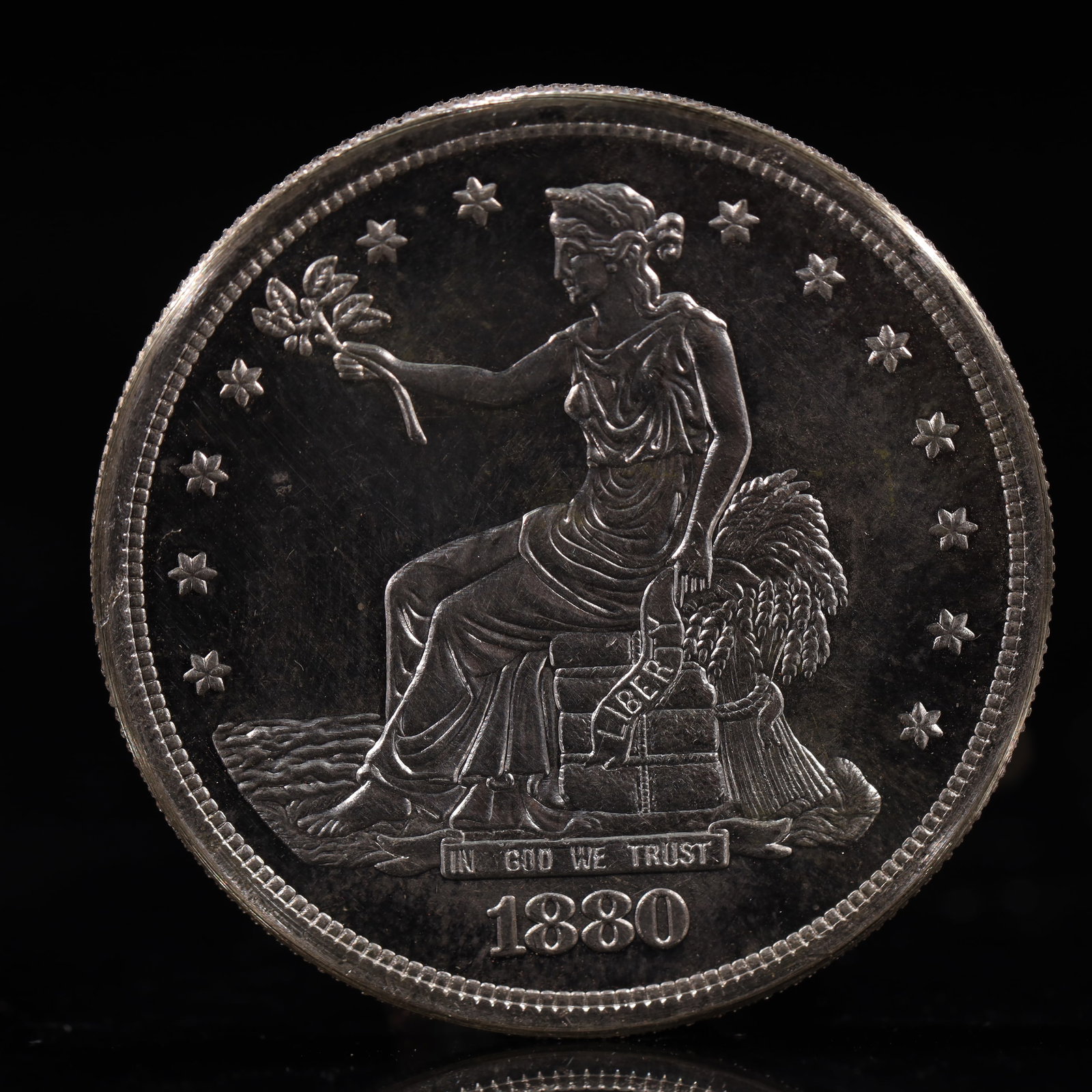 USA Trade Dollar 1880 Coin: American coin. Obverse: Liberty seated on a pedestal facing the sea to the left holding olive branches surrounded by 13 stars. IN GOD WE TRUST / LIBERTY / 1880. Reverse: An eagle holding branches with