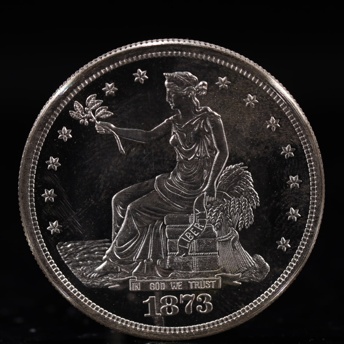 USA Trade Dollar 1873 Coin: American coin. Obverse: Liberty seated on a pedestal facing the sea to the left holding olive branches surrounded by 13 stars. IN GOD WE TRUST / LIBERTY / 1873. Reverse: An eagle holding branches with