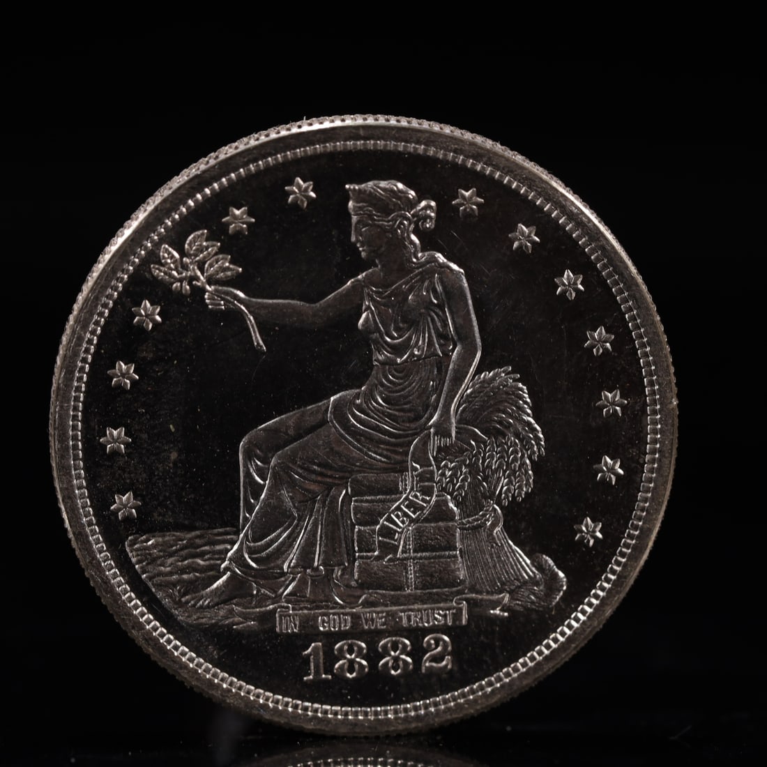 USA Trade Dollar 1882 Coin: American coin. Obverse: Liberty seated on a pedestal facing the sea to the left holding olive branches surrounded by 13 stars. IN GOD WE TRUST / LIBERTY / 1882. Reverse: An eagle holding branches with