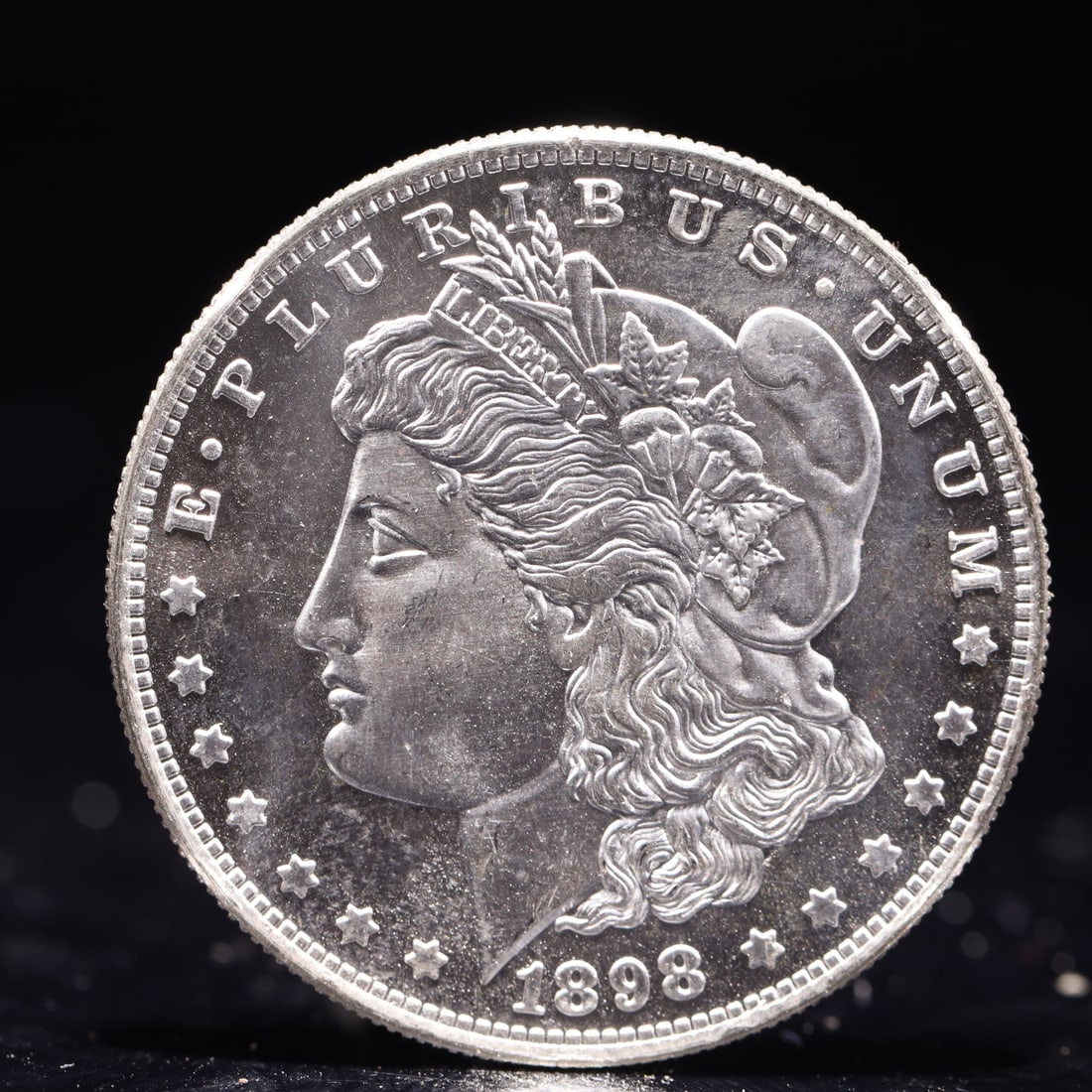 USA Morgan Dollar 1898 Coin: Obv: profile bust with date below and E PLURIBUS UNUM legend and stars around. Rev: eagle with In God we trust above within wreath with UNITED STATES OF AMERICA ONE DOLLAR legend. IN GOD WE TRUST / LI