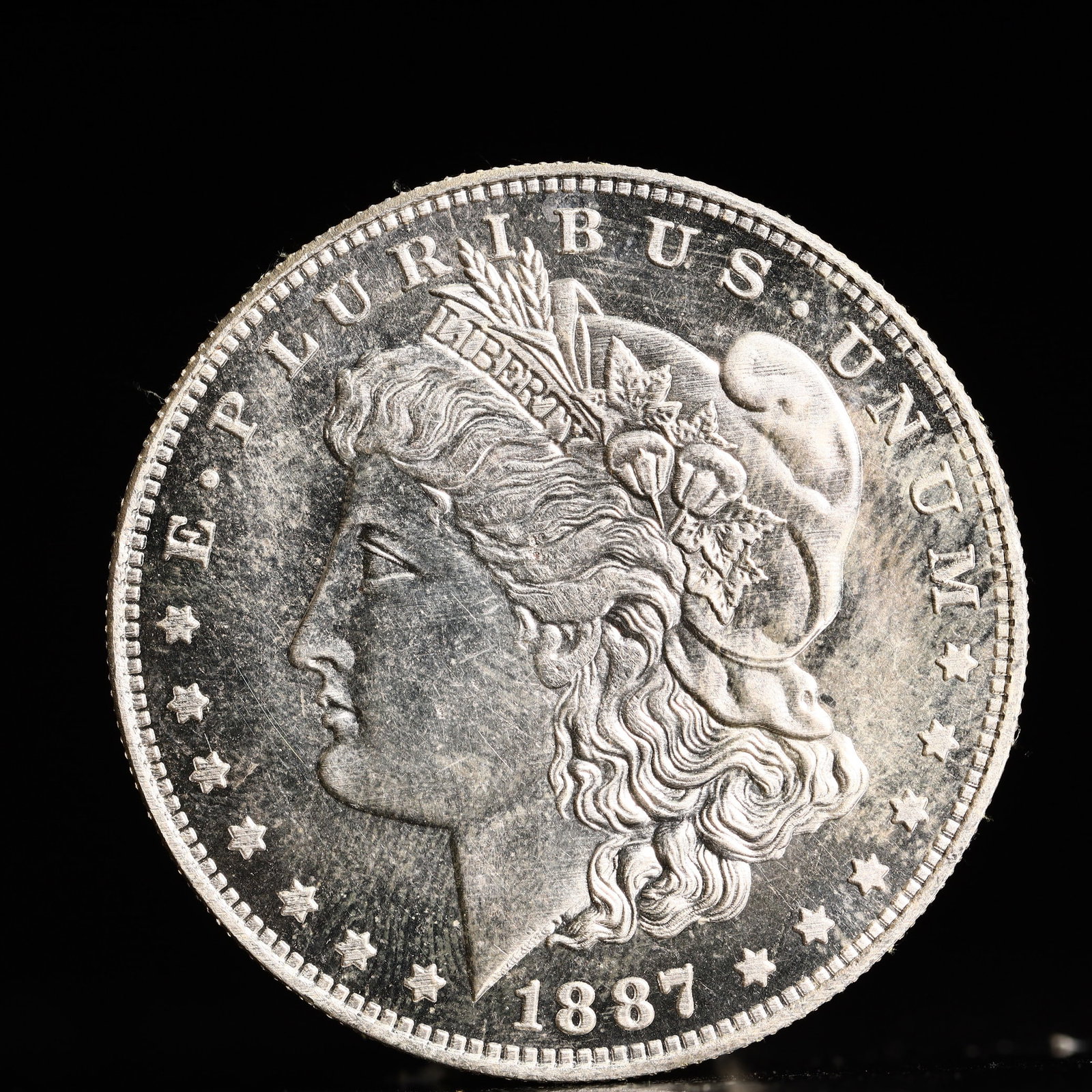 USA Morgan Dollar 1887 Coin: Obv: profile bust with date below and E PLURIBUS UNUM legend and stars around. Rev: eagle with In God we trust above within wreath with UNITED STATES OF AMERICA ONE DOLLAR legend. IN GOD WE TRUST / LI