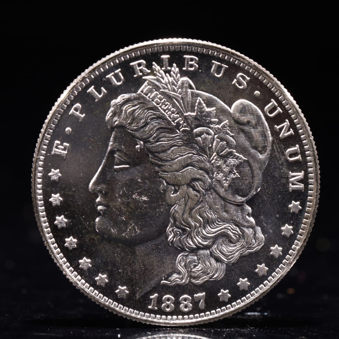 USA Morgan Dollar 1887 Coin: Obv: profile bust with date below and E PLURIBUS UNUM legend and stars around. Rev: eagle with In God we trust above within wreath with UNITED STATES OF AMERICA ONE DOLLAR legend. IN GOD WE TRUST / LI