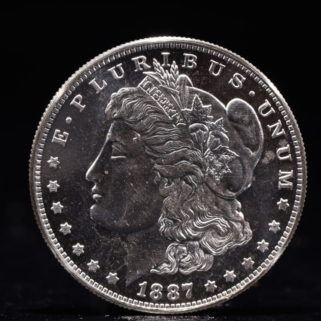 USA Morgan Dollar 1887 Coin: Obv: profile bust with date below and E PLURIBUS UNUM legend and stars around. Rev: eagle with In God we trust above within wreath with UNITED STATES OF AMERICA ONE DOLLAR legend. IN GOD WE TRUST / LI
