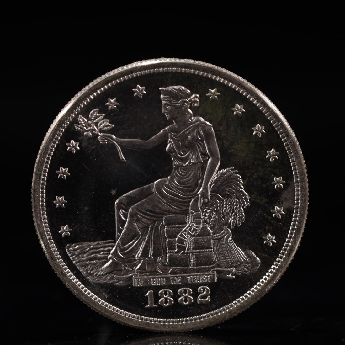 USA Trade Dollar 1882 Coin: American coin. Obverse: Liberty seated on a pedestal facing the sea to the left holding olive branches surrounded by 13 stars. IN GOD WE TRUST / LIBERTY / 1882. Reverse: An eagle holding branches