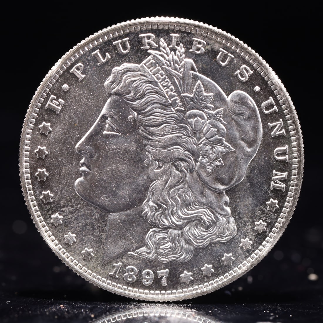 USA Morgan Dollar 1897 Coin: Obv: profile bust with date below and E PLURIBUS UNUM legend and stars around. Rev: eagle with In God we trust above within wreath with UNITED STATES OF AMERICA ONE DOLLAR legend. IN GOD WE TRUST / LI