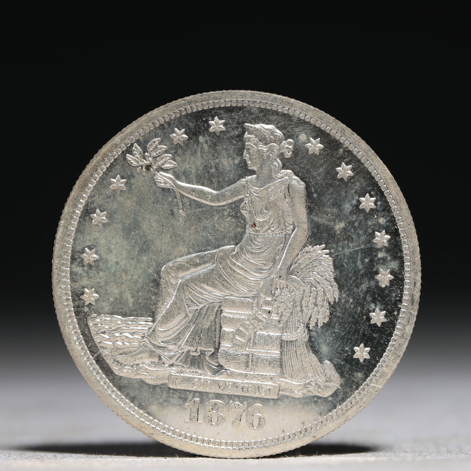 USA Trade Dollar 1876 Coin: American coin. Obverse: Liberty seated on a pedestal facing the sea to the left holding olive branches surrounded by 13 stars. IN GOD WE TRUST / LIBERTY / 1876. Reverse: An eagle holding branches with