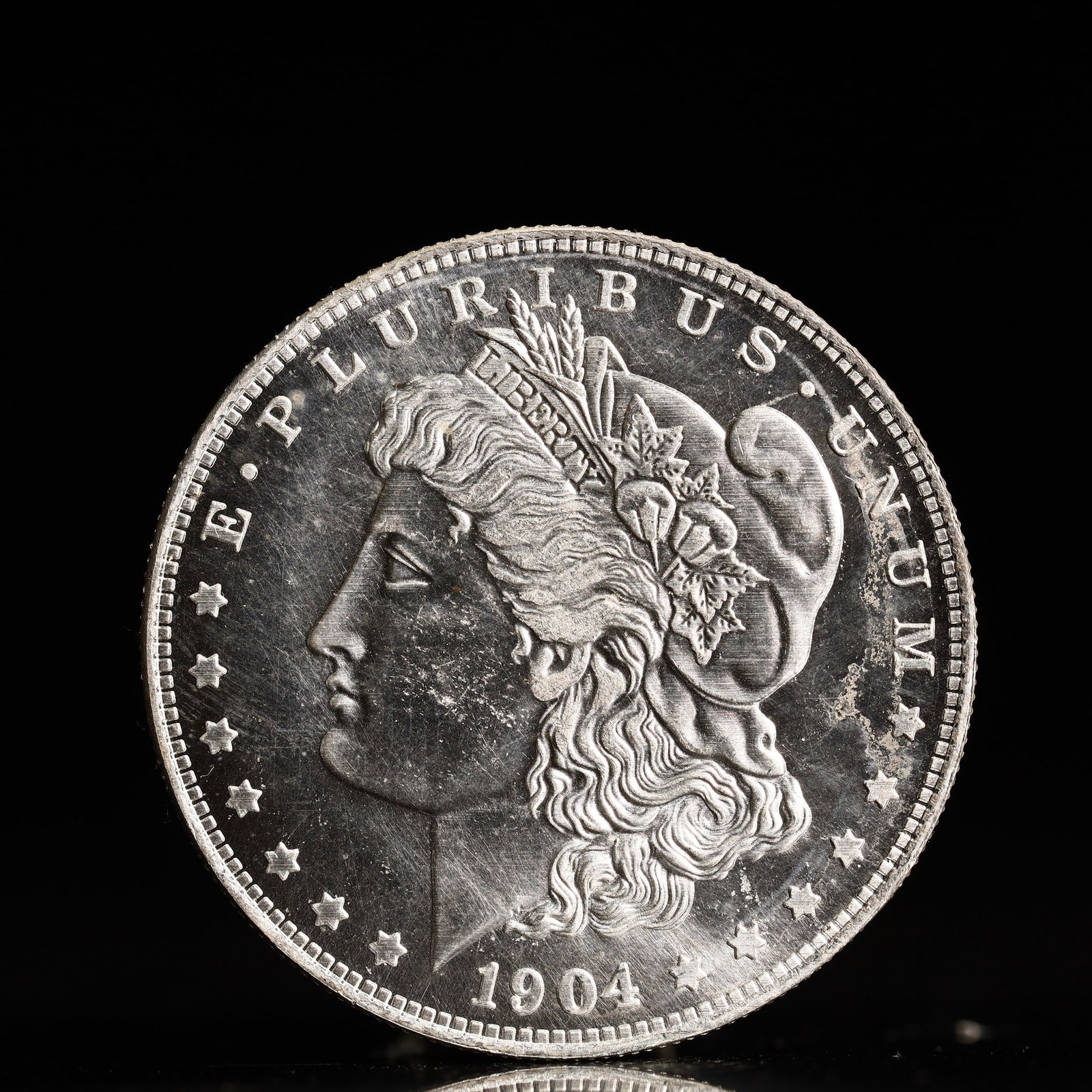 USA Morgan Dollar 1904 Coin: Obv: profile bust with date below and E PLURIBUS UNUM legend and stars around. Rev: eagle with In God we trust above within wreath with UNITED STATES OF AMERICA ONE DOLLAR legend. IN GOD WE TRUST / LI