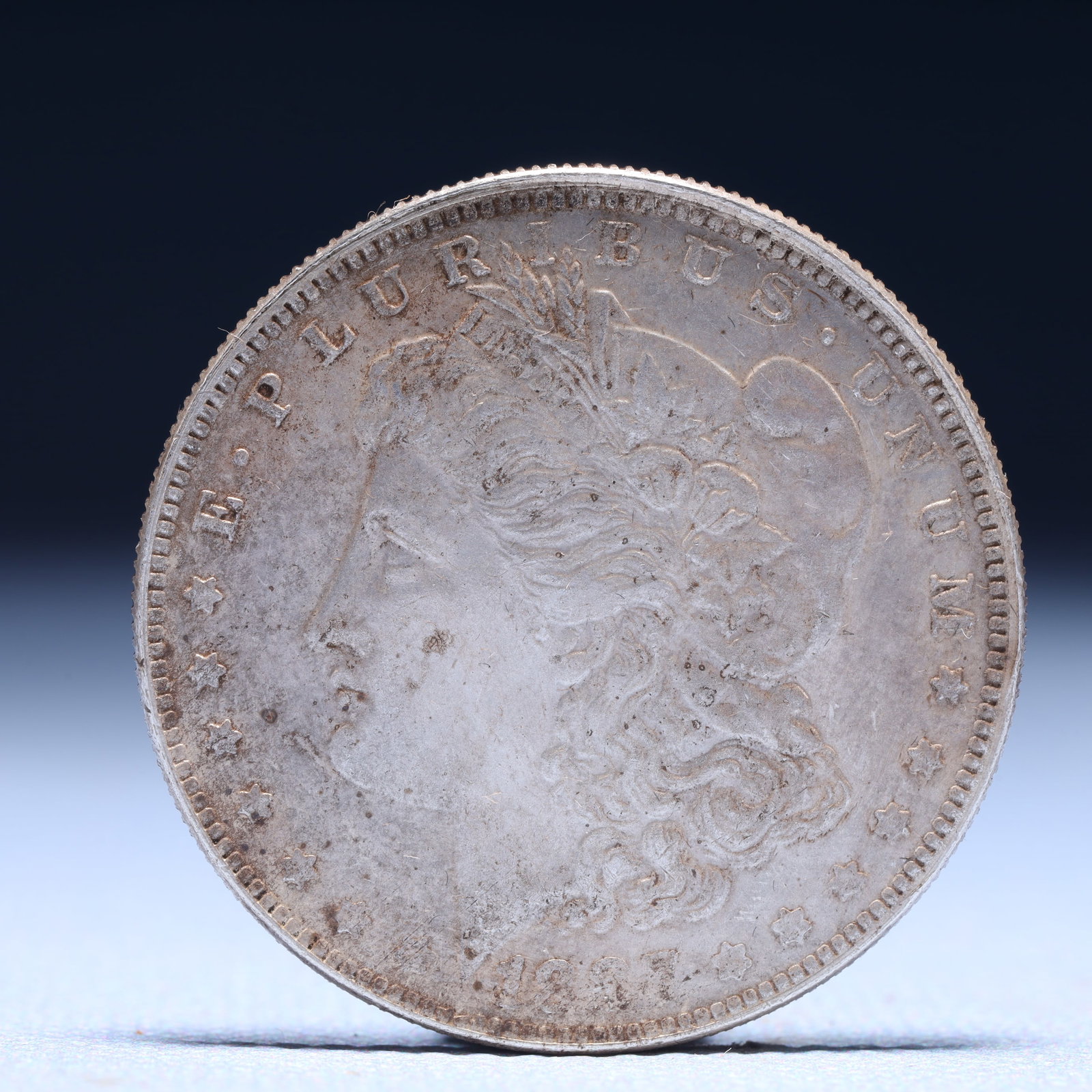 USA Morgan Dollar 1887 Coin: Obv: profile bust with date below and E PLURIBUS UNUM legend and stars around. Rev: eagle with In God we trust above within wreath with UNITED STATES OF AMERICA ONE DOLLAR legend. IN GOD WE TRUST / LI