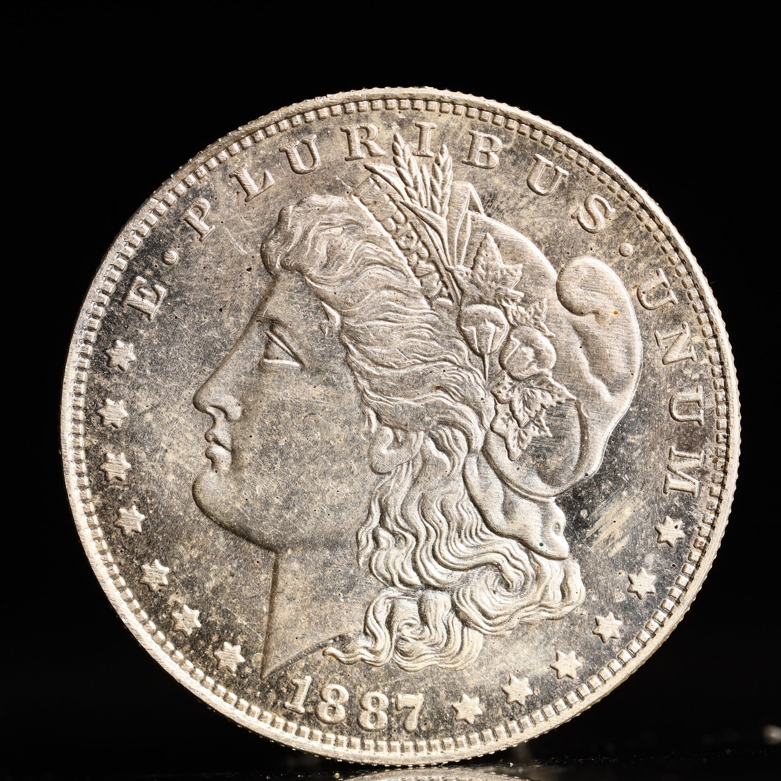 USA Morgan Dollar 1887 Coin: Obv: profile bust with date below and E PLURIBUS UNUM legend and stars around. Rev: eagle with In God we trust above within wreath with UNITED STATES OF AMERICA ONE DOLLAR legend. IN GOD WE TRUST /