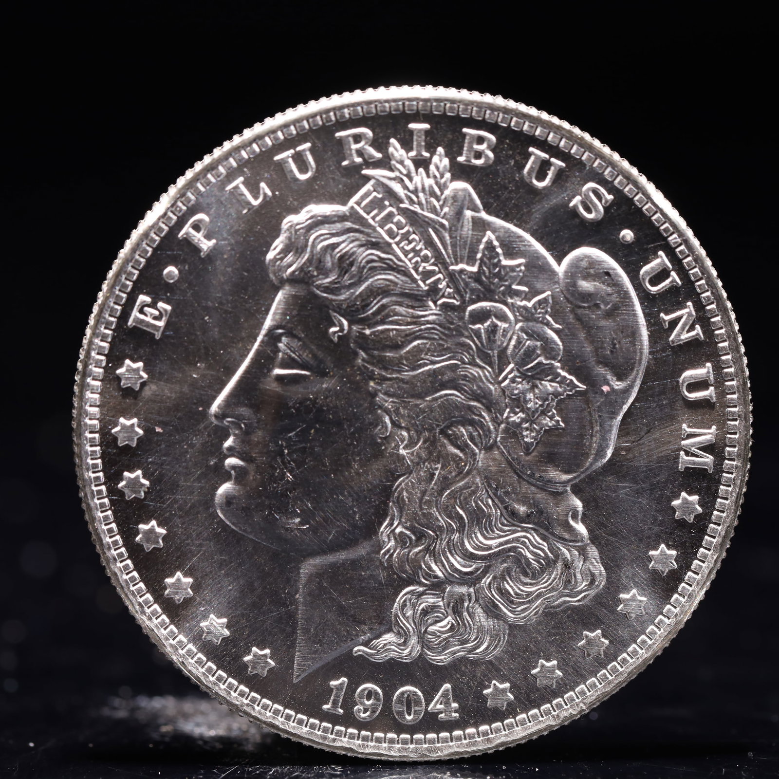 USA Morgan Dollar 1904 Coin: Obv: profile bust with date below and E PLURIBUS UNUM legend and stars around. Rev: eagle with In God we trust above within wreath with UNITED STATES OF AMERICA ONE DOLLAR legend. IN GOD WE TRUST / LI