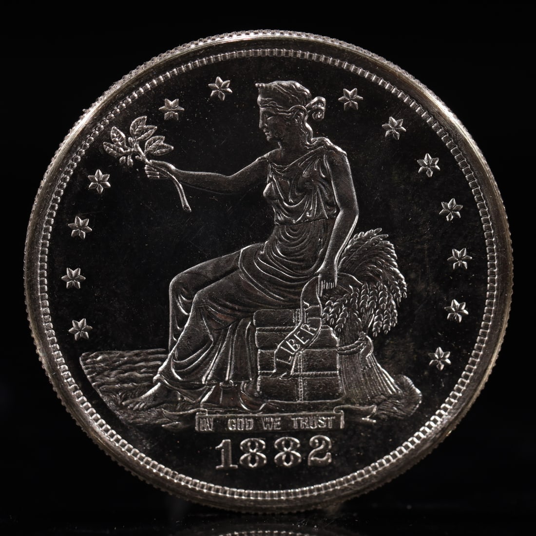 USA Trade Dollar 1882 Coin: American coin. Obverse: Liberty seated on a pedestal facing the sea to the left holding olive branches surrounded by 13 stars. IN GOD WE TRUST / LIBERTY / 1882. Reverse: An eagle holding branches with